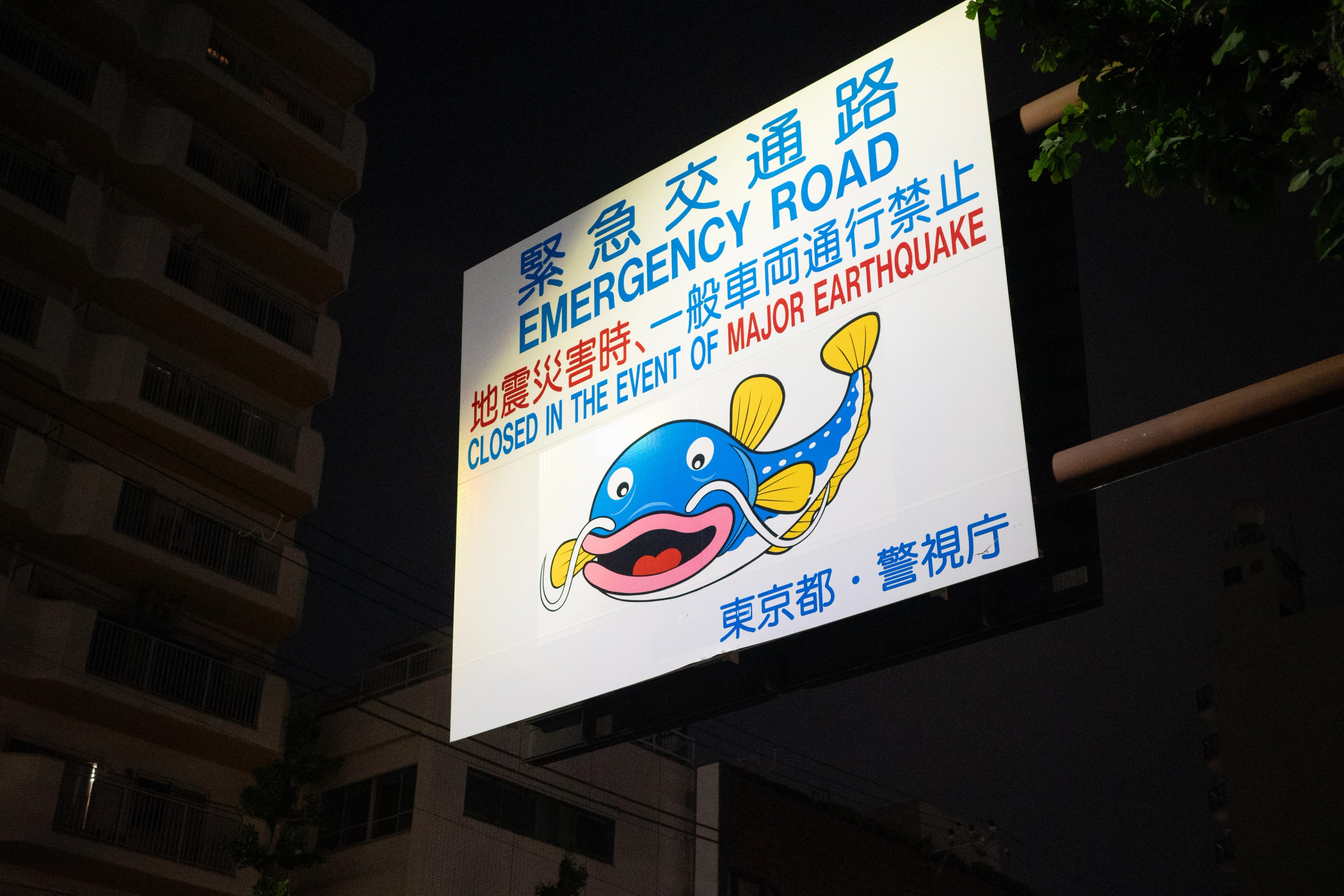 An illuminated billboard with a cartoon mascot rises above a street.