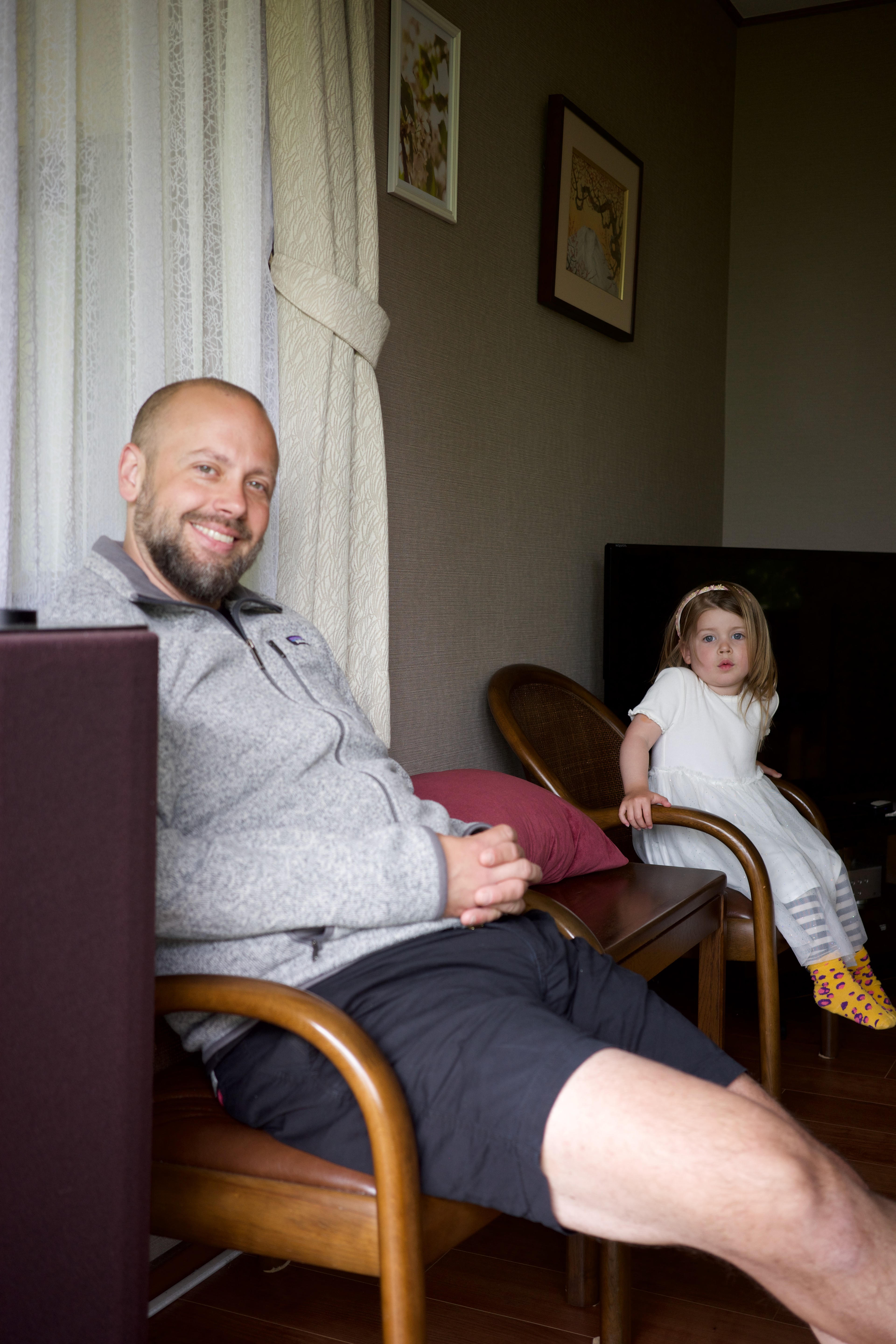 An adult and child sit together in a living room.