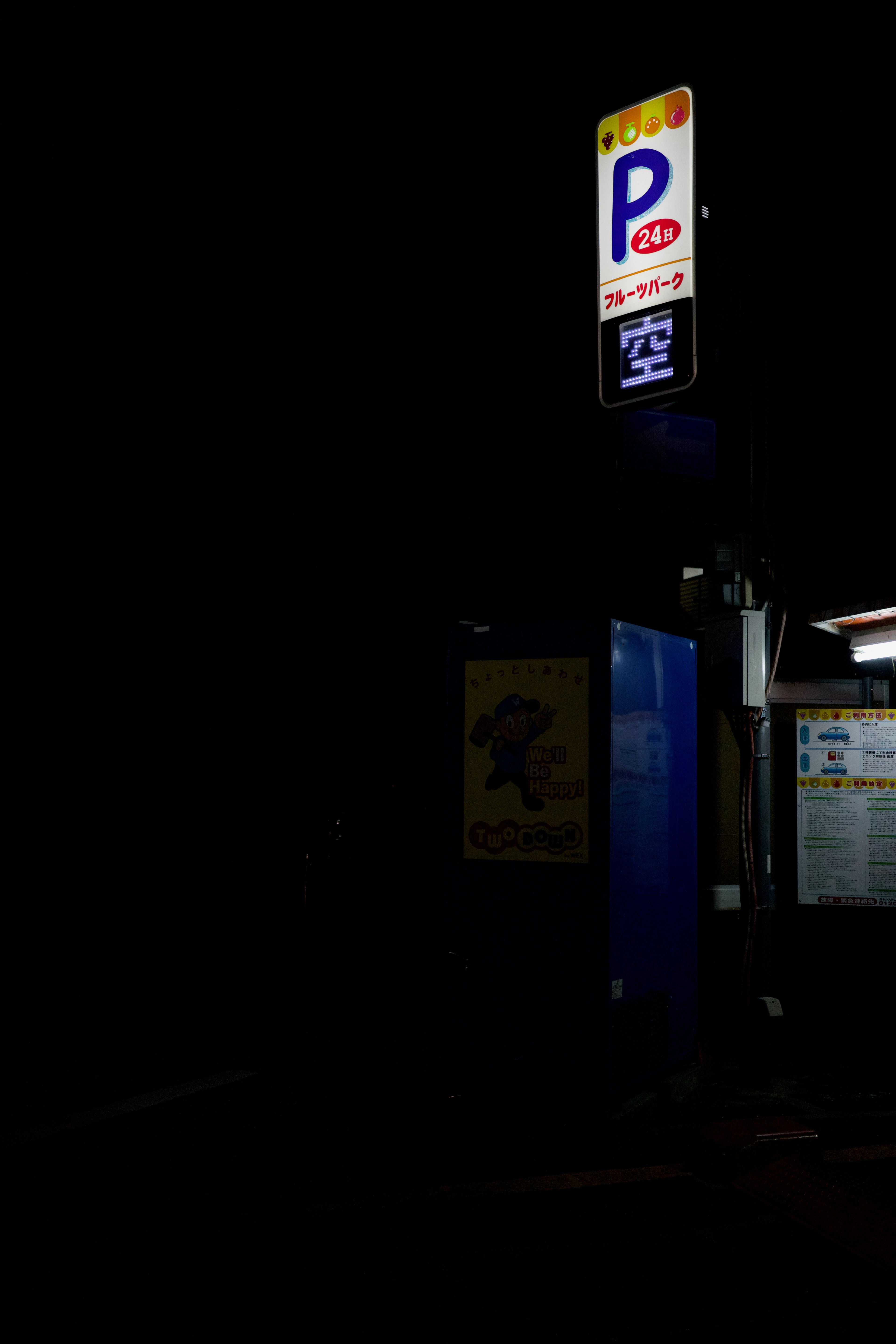 A blue parking sign glows above a dark street.
