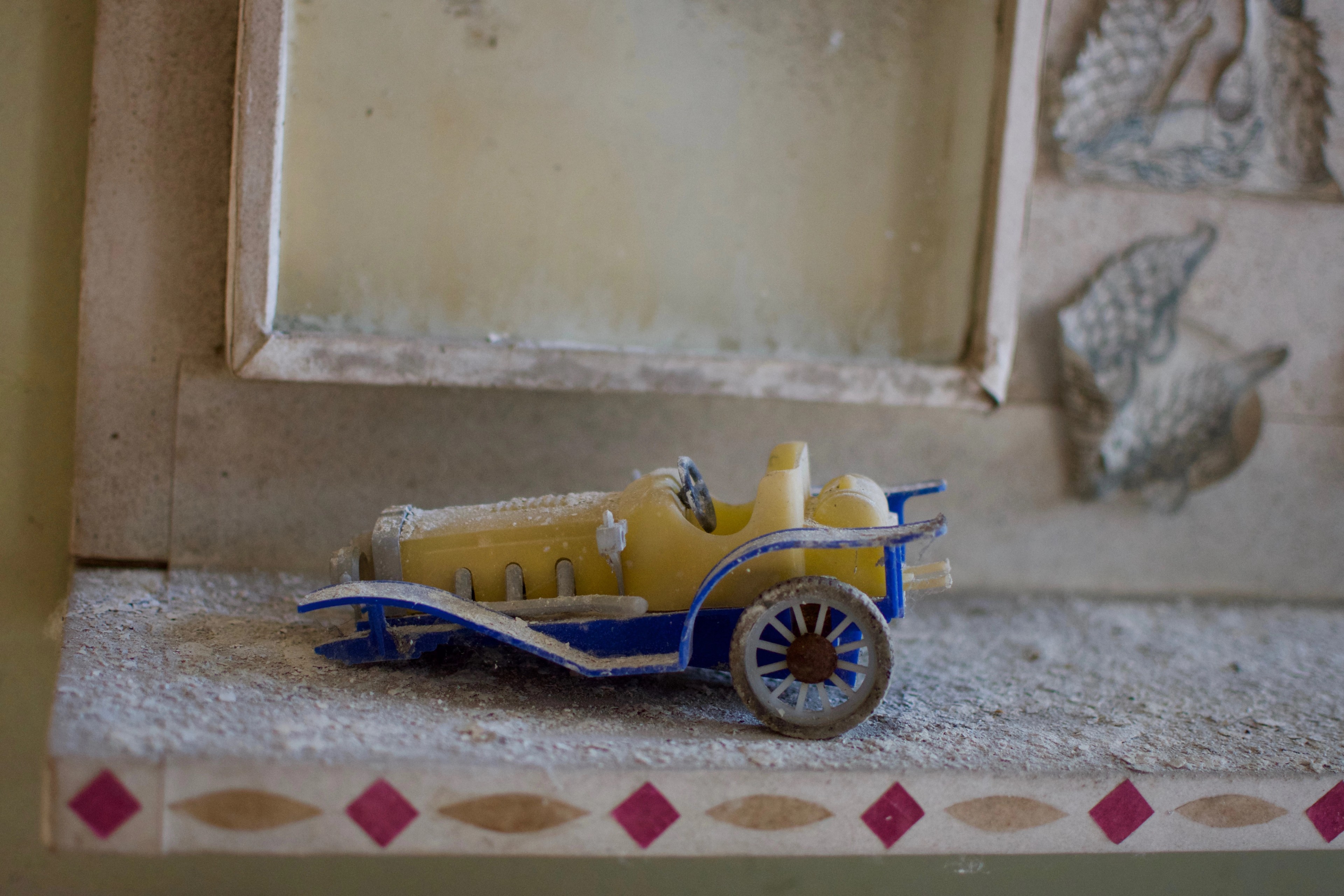 A small blue-and-yellow toy cart sits on a ledge.