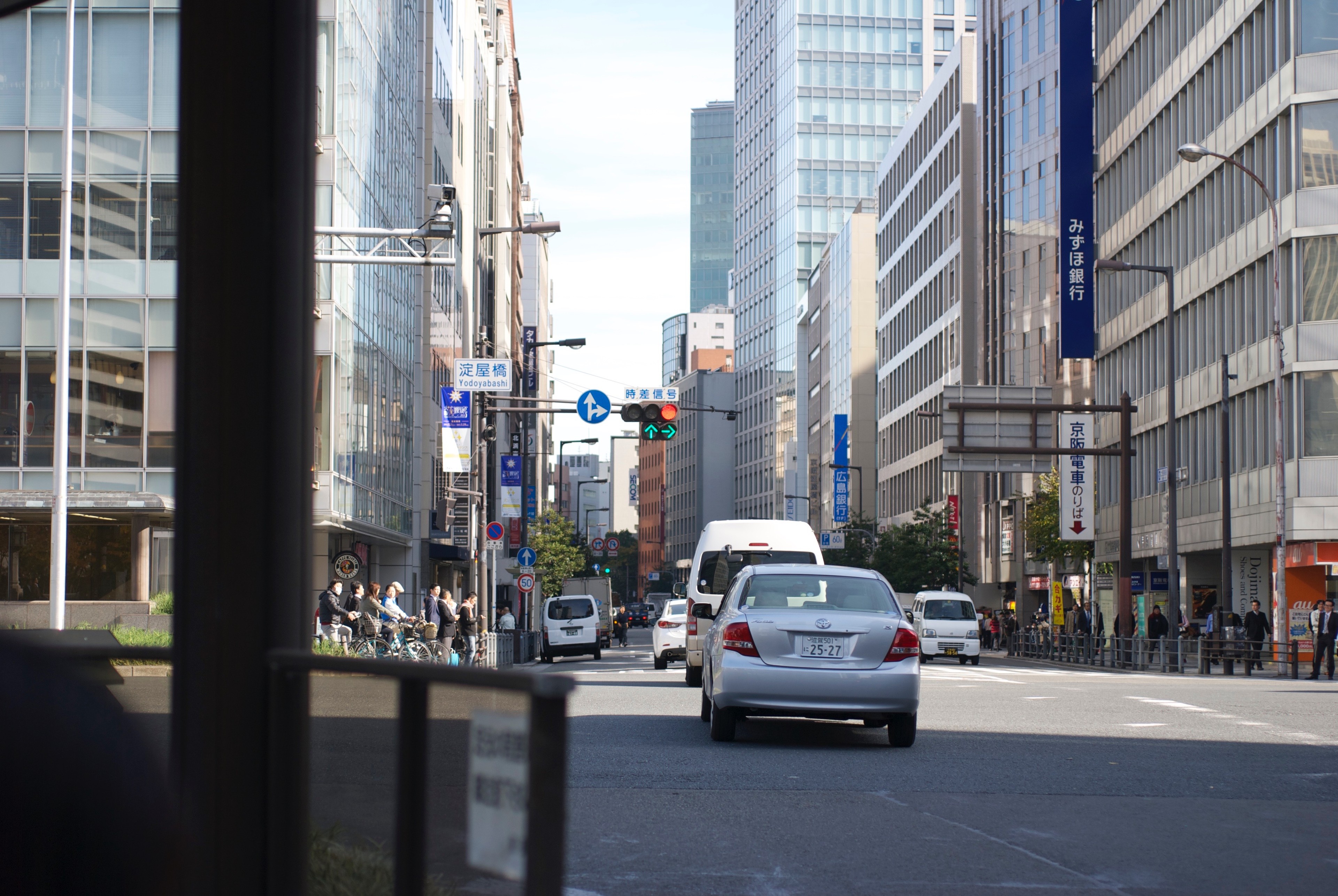 City traffic is seen through glass from inside a building.