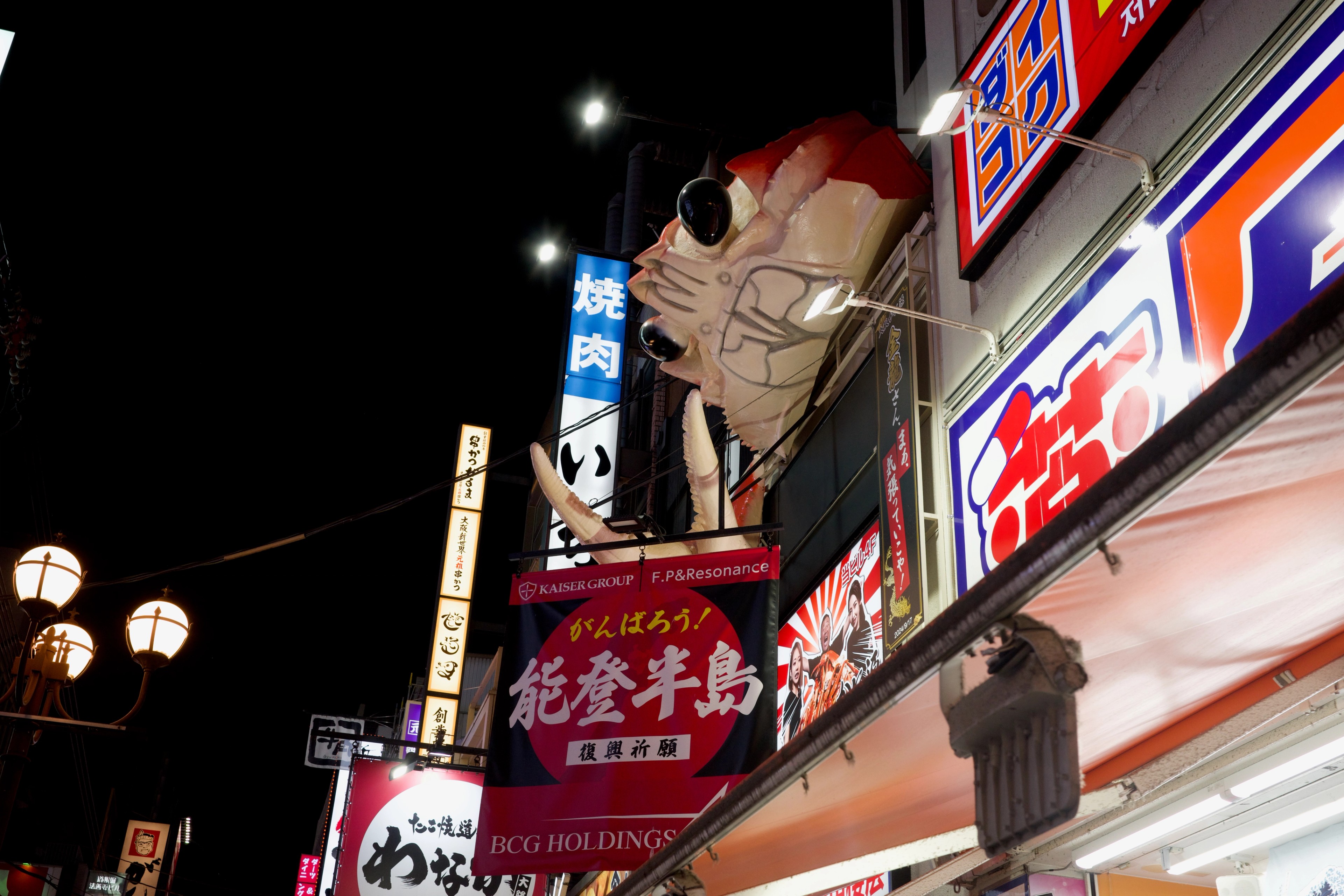A giant illuminated crab sign hangs over a restaurant.