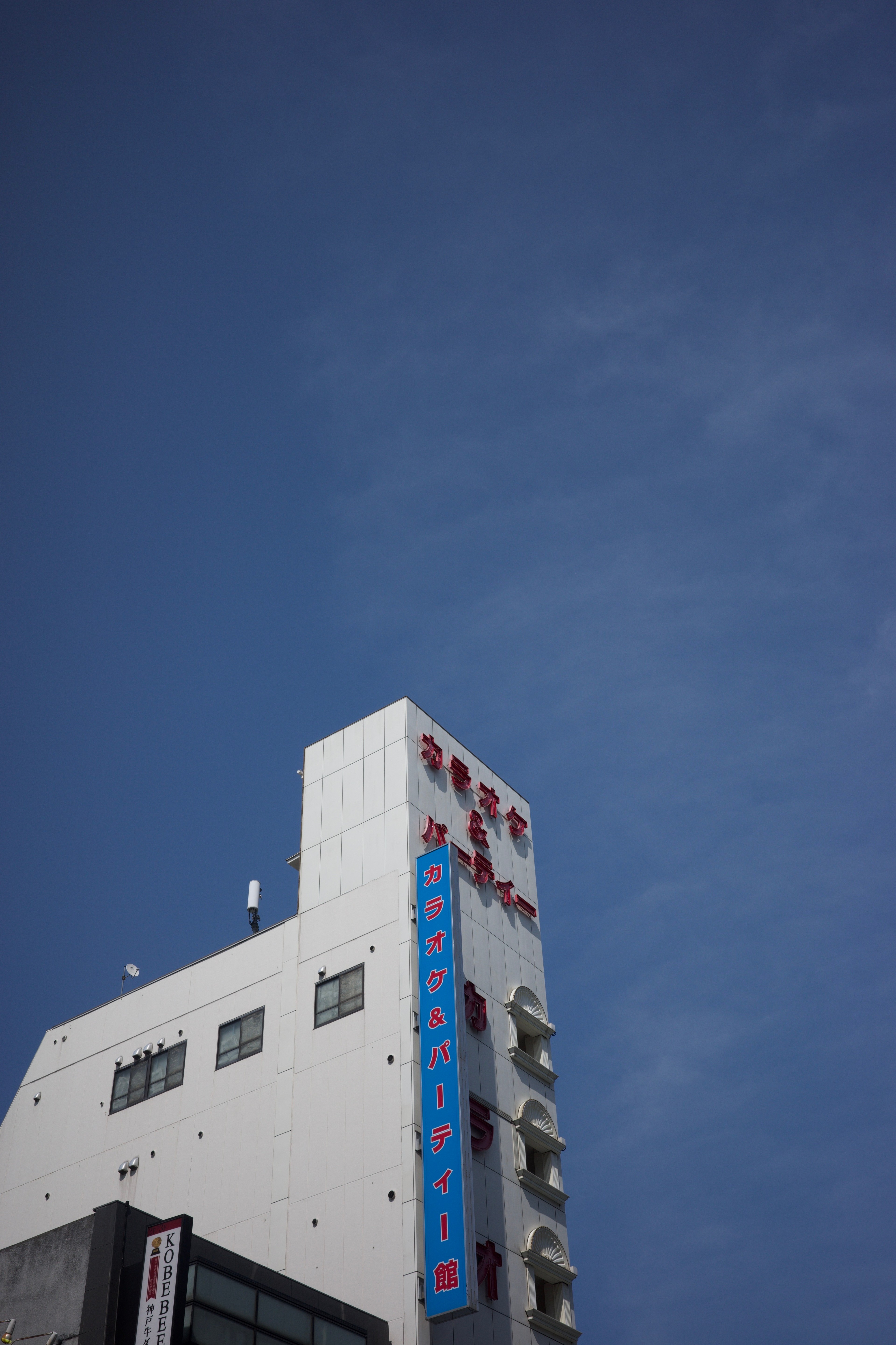A white office building viewed from street level against a clear sky.