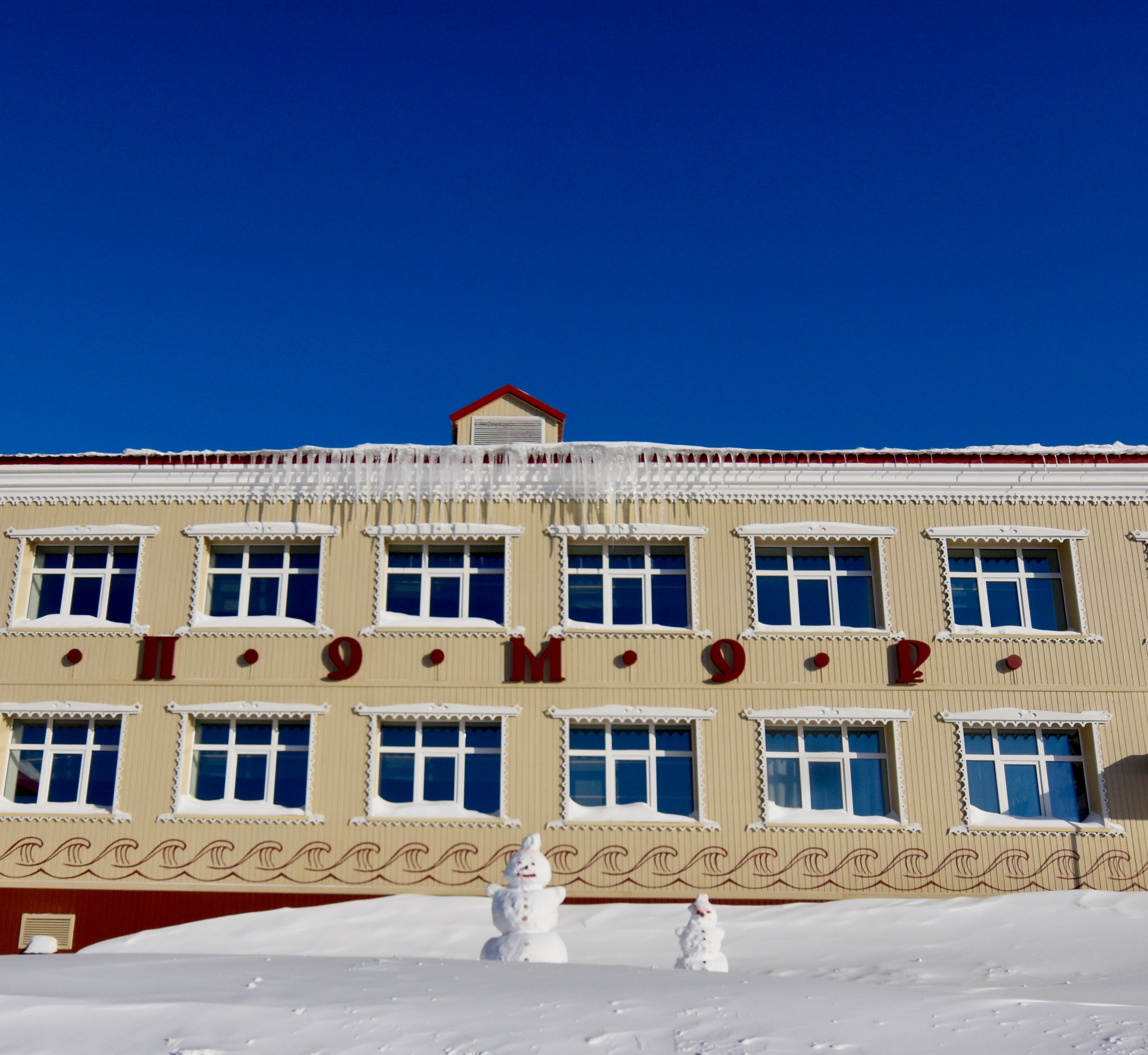A yellow building stands against a clear blue sky.