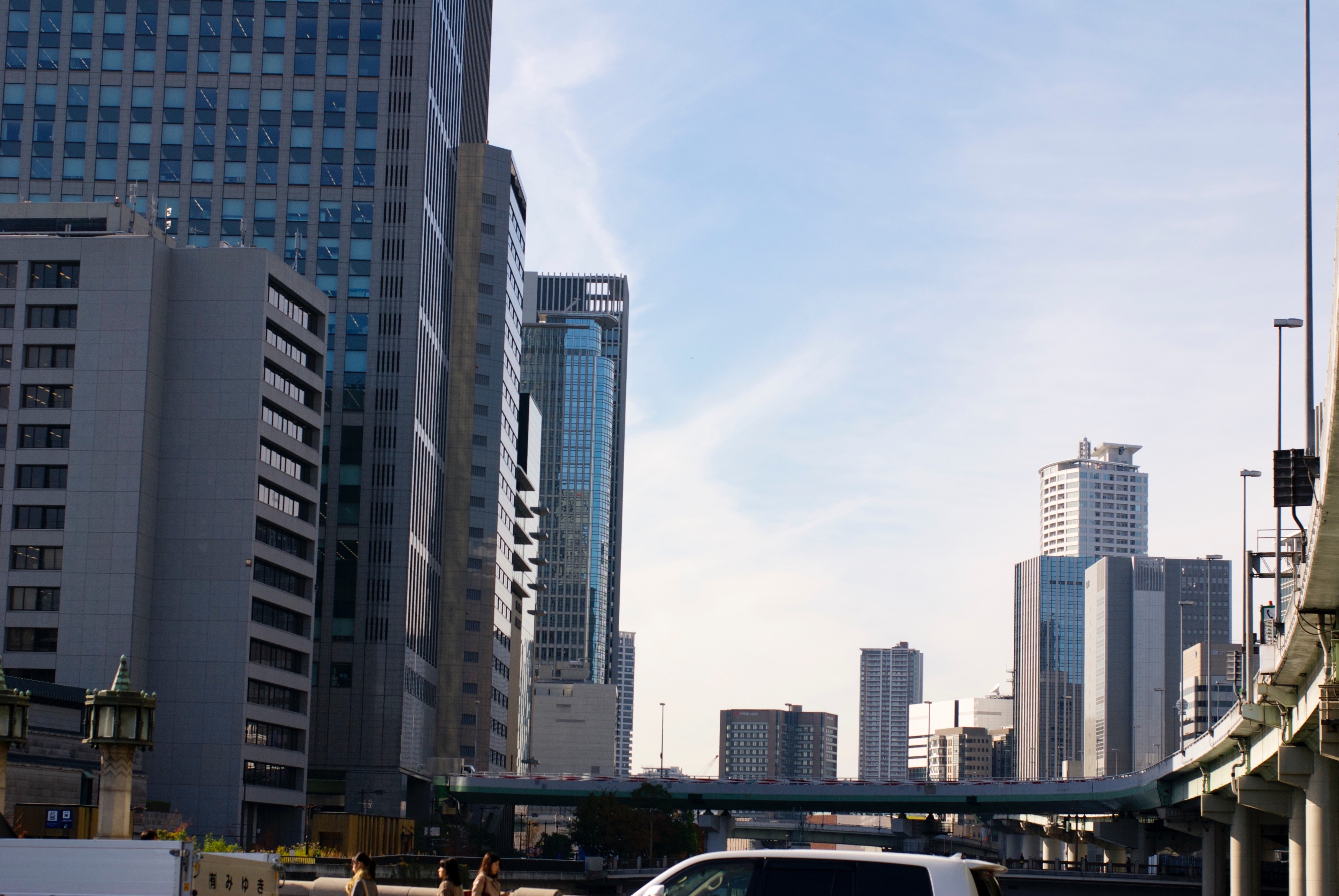 A road passes beneath an elevated railway toward a distant tower.