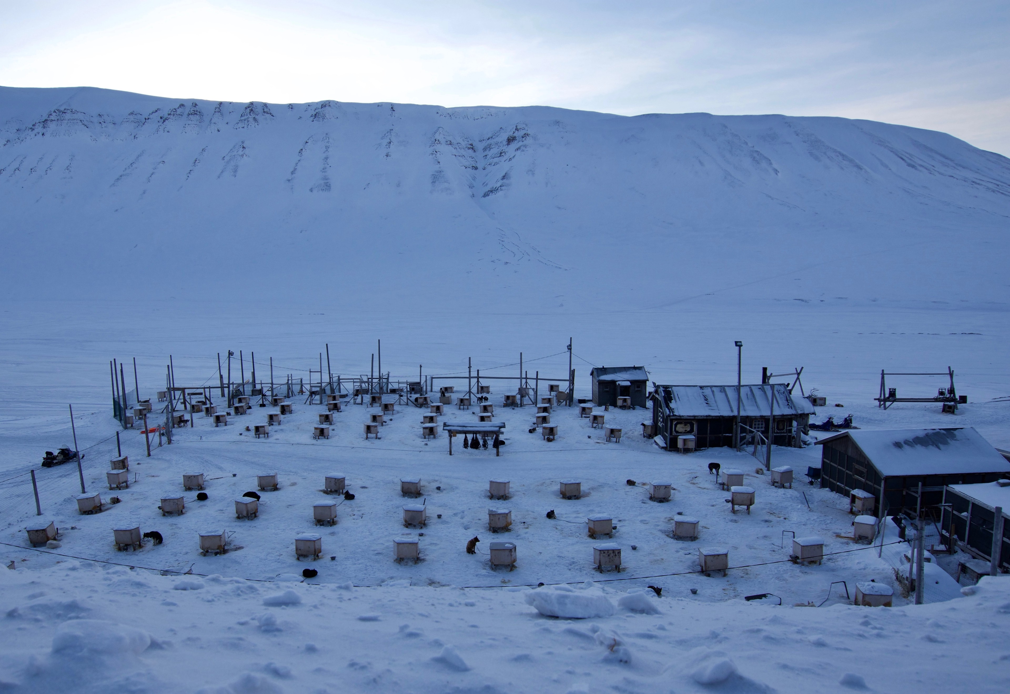 Rows of small buildings sit below a mountain in winter.