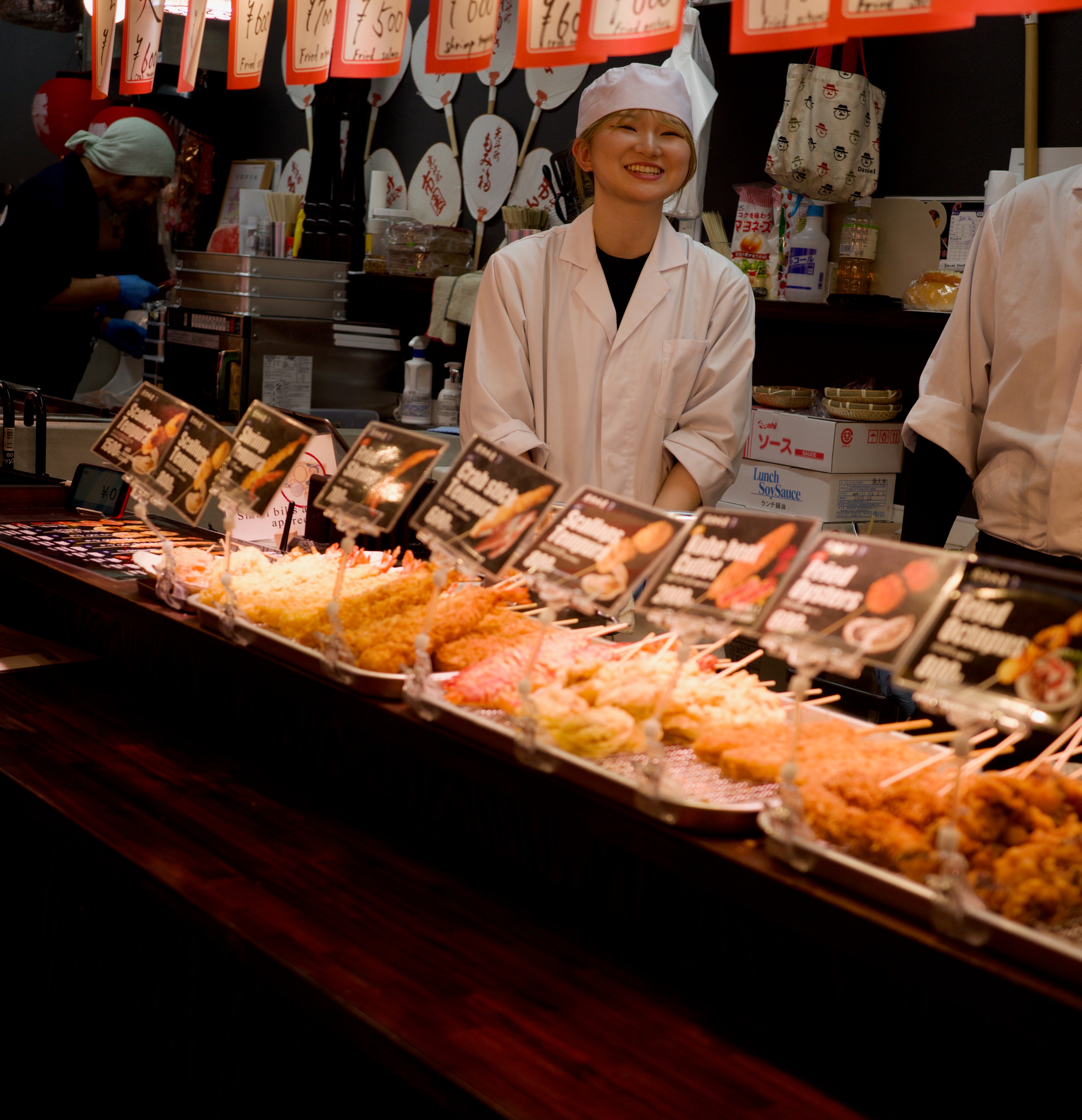 A vendor serves customers behind a food counter.