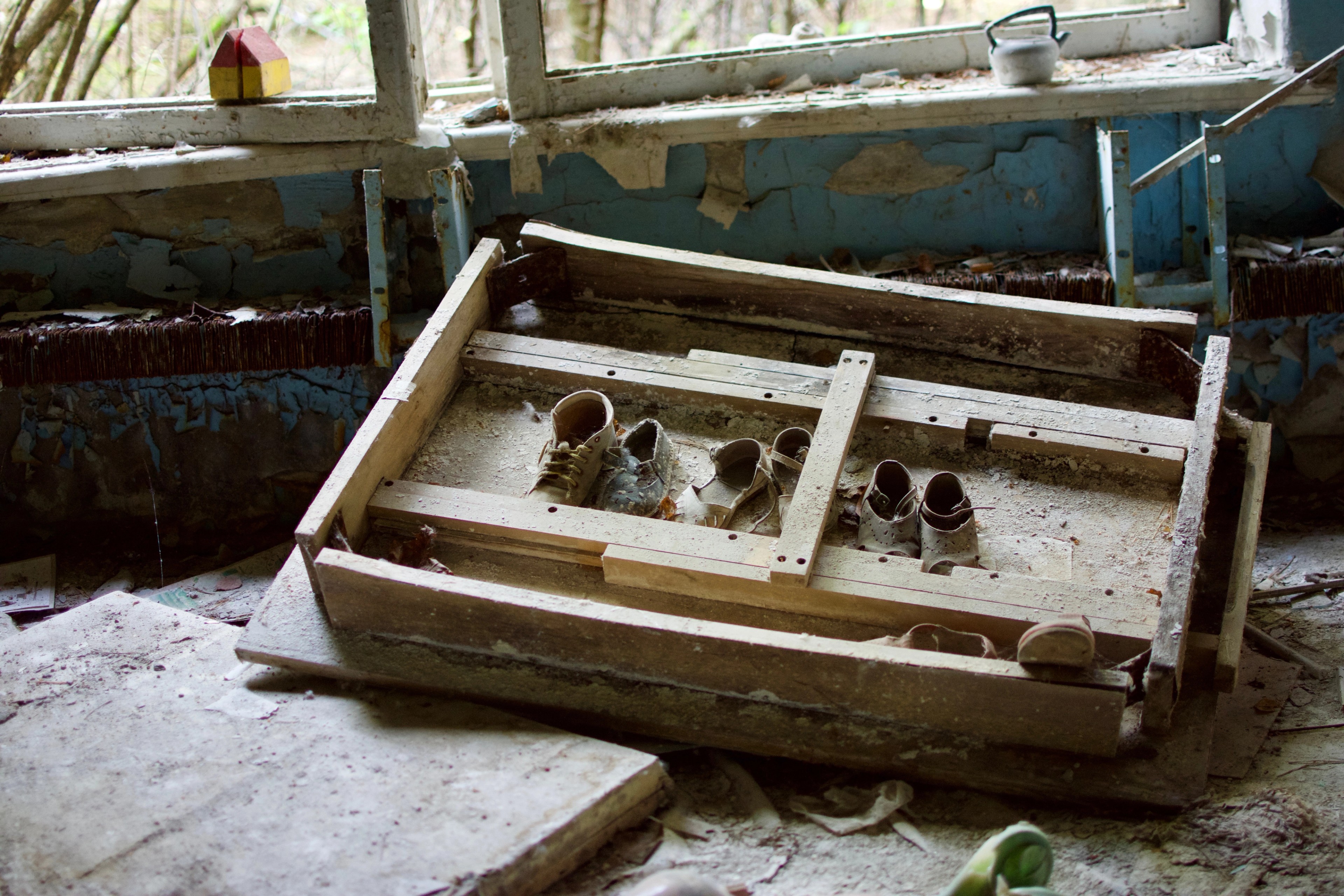 An empty wooden toy cradle rests in a blue-painted room.