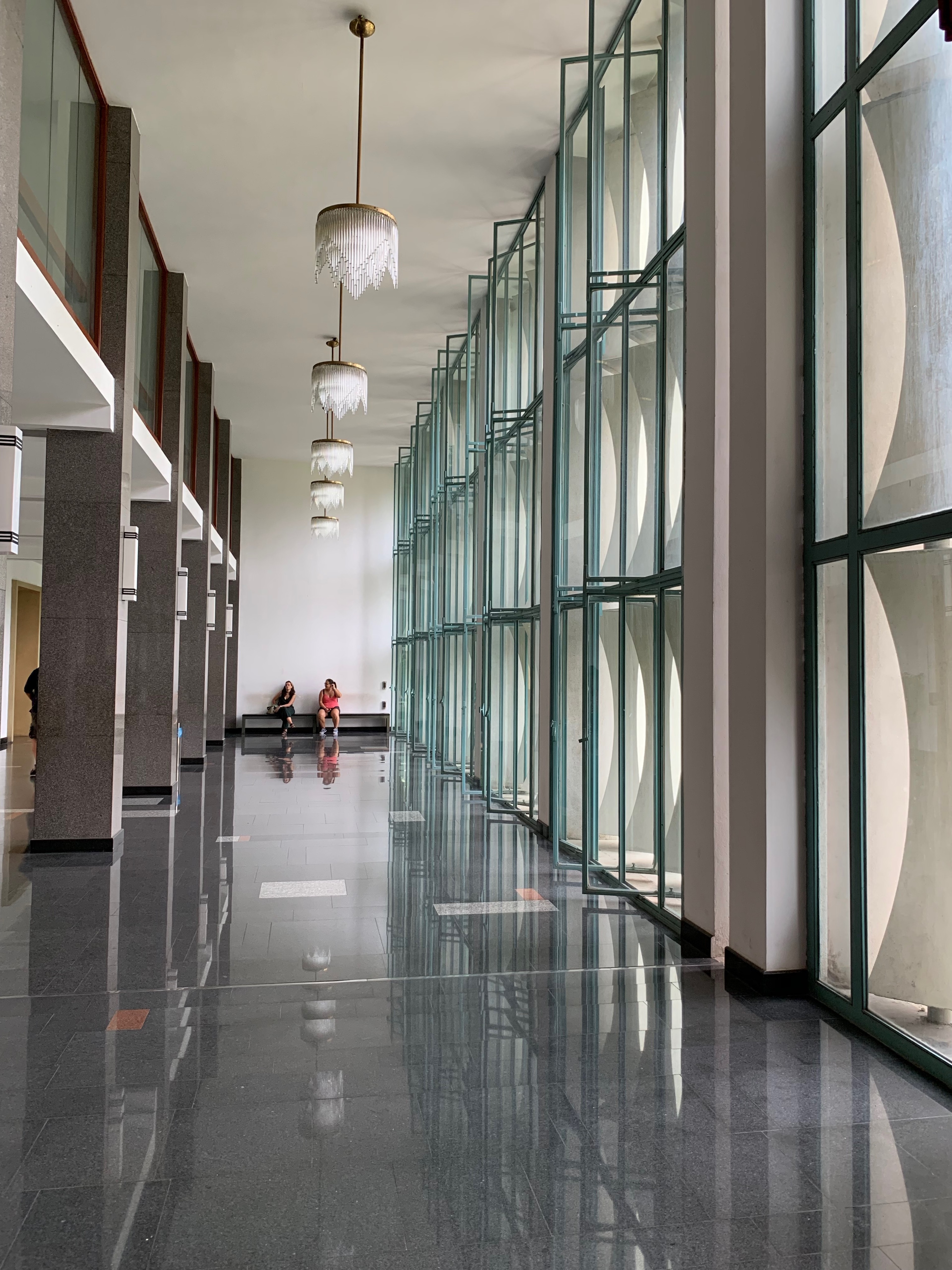 A modern corridor with floor-to-ceiling windows and a polished floor.
