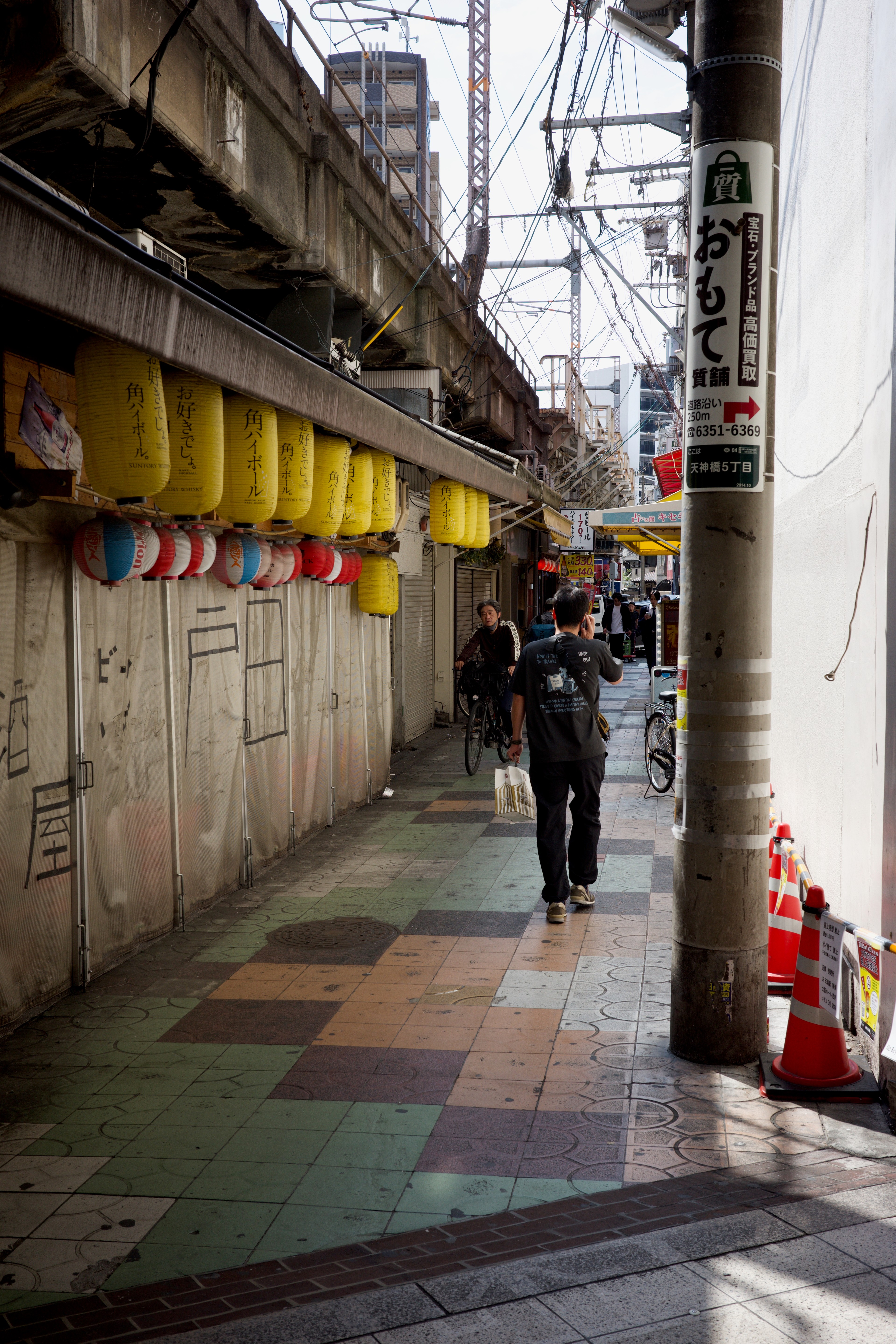 A covered shopping arcade with storefronts and pedestrians.