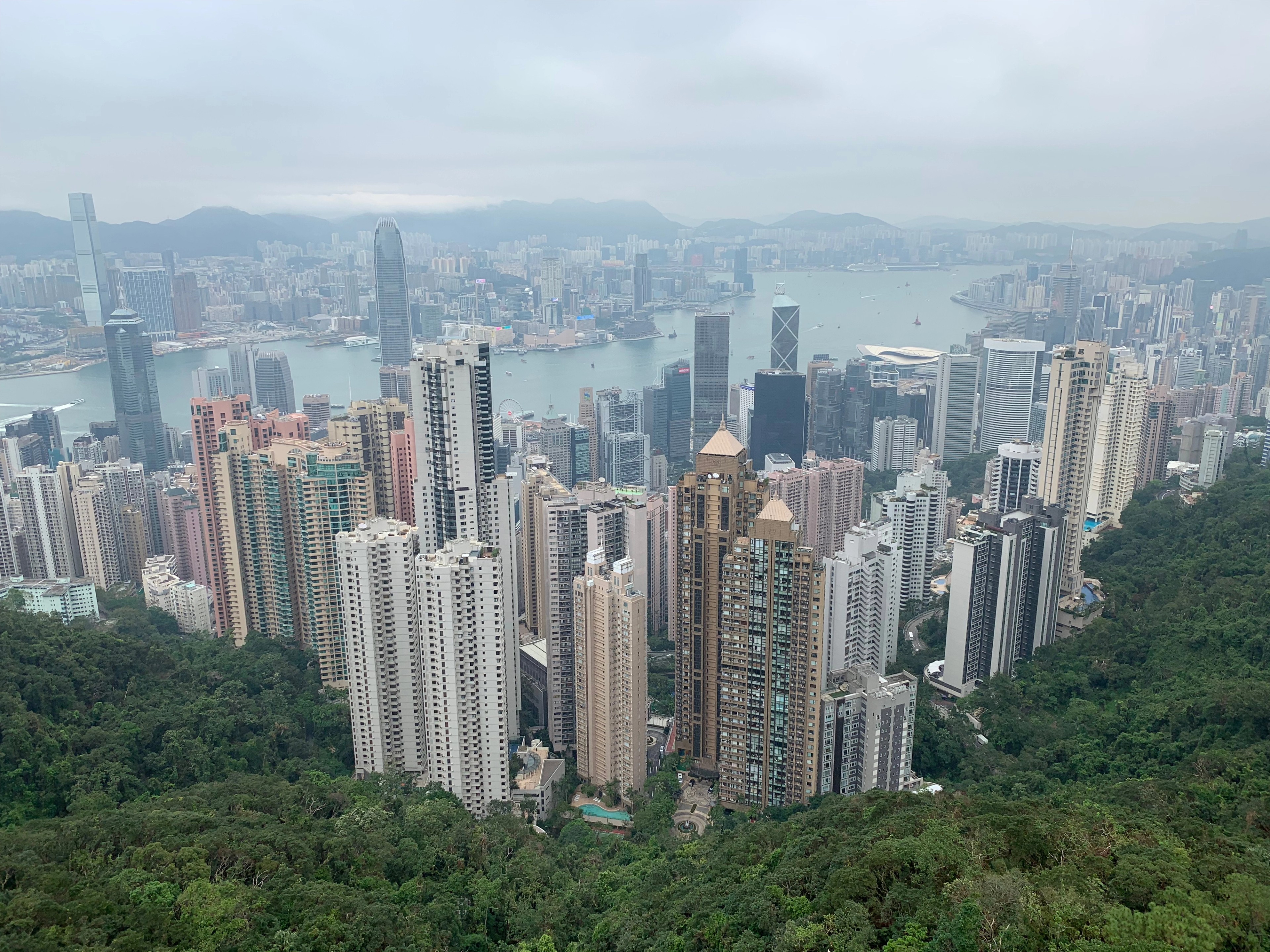 Hong Kong high-rise buildings beneath green hills in daylight.
