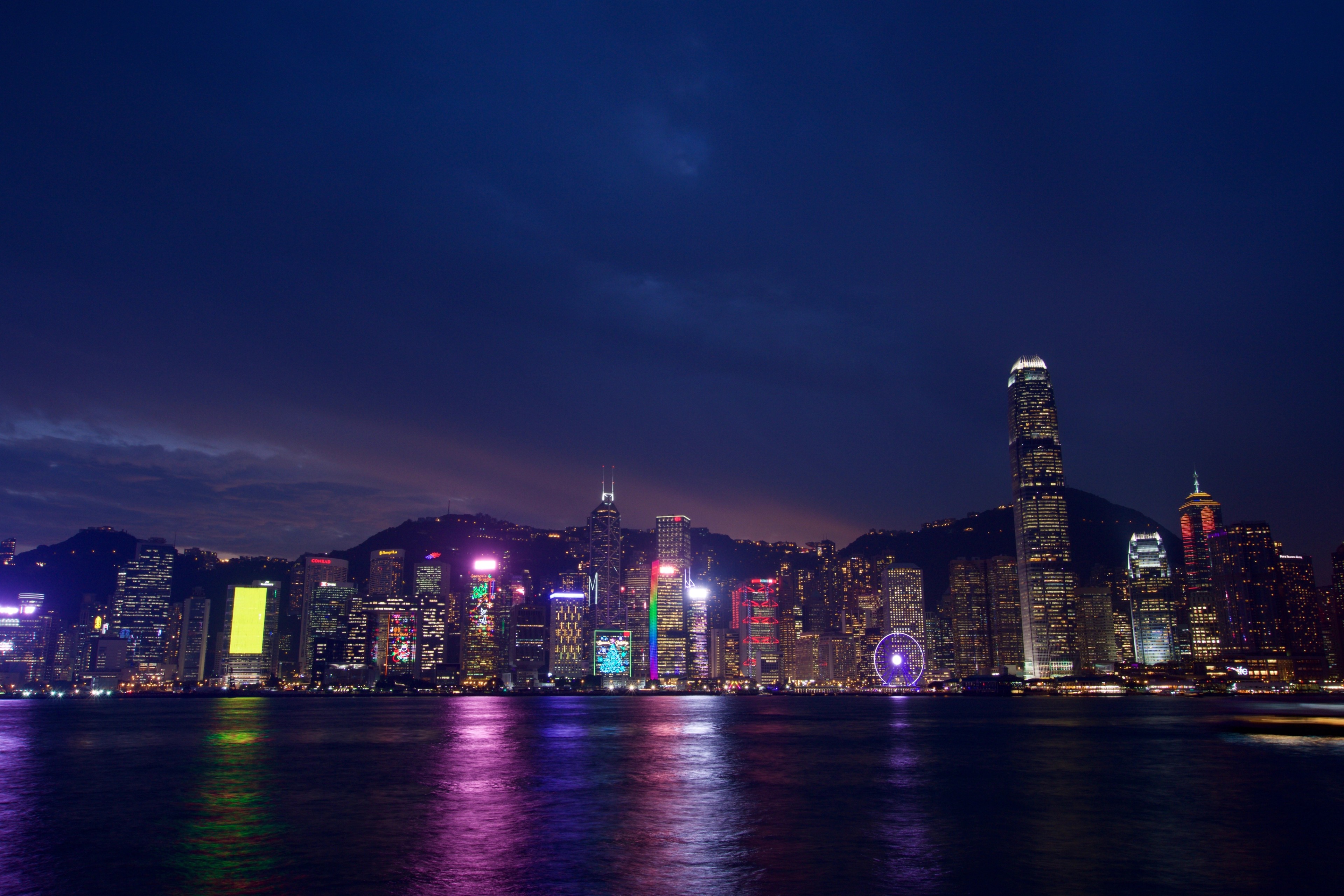 Hong Kong’s illuminated skyline rises across the harbor at night.
