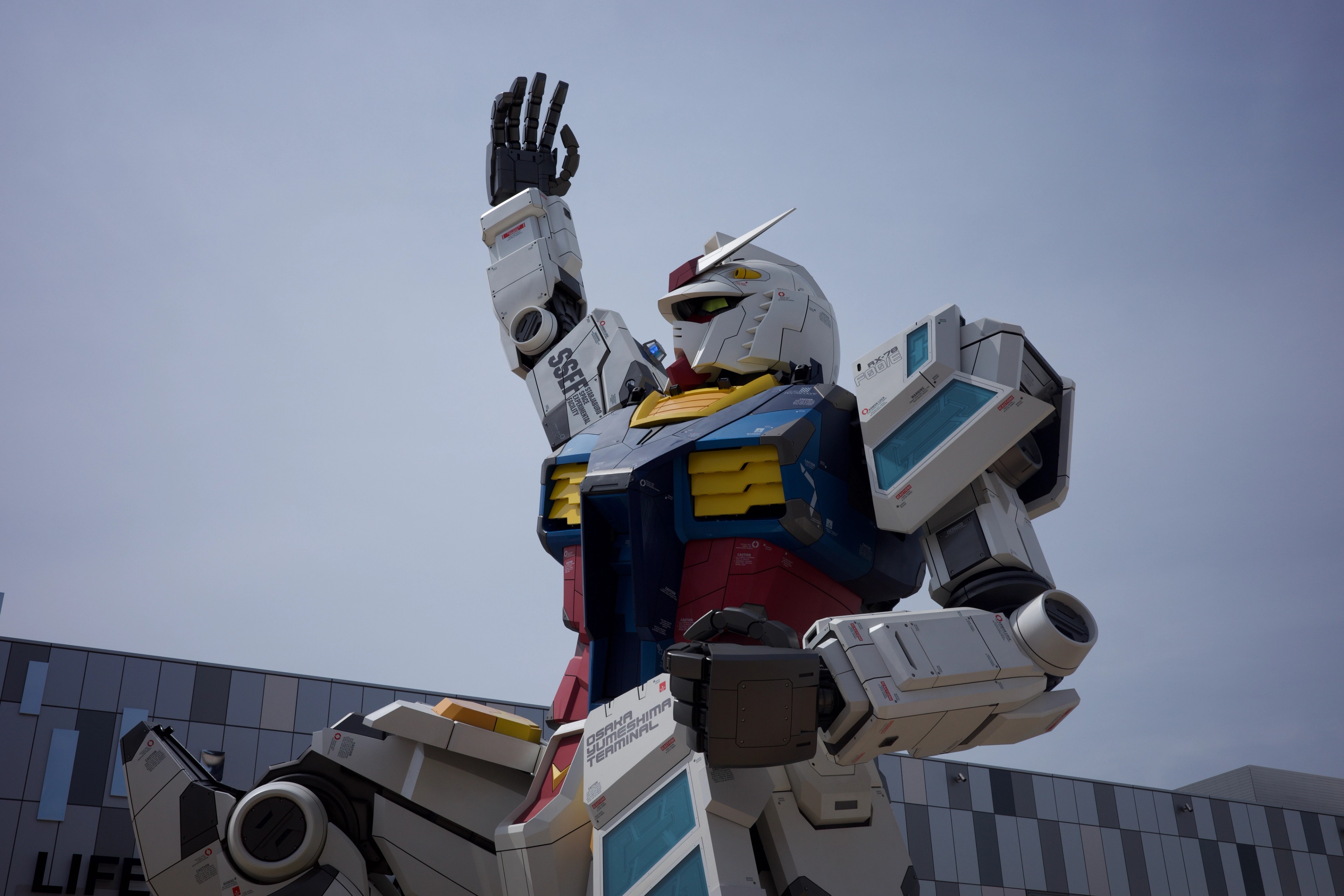 A giant robot sculpture raises one hand against a cloudy sky.