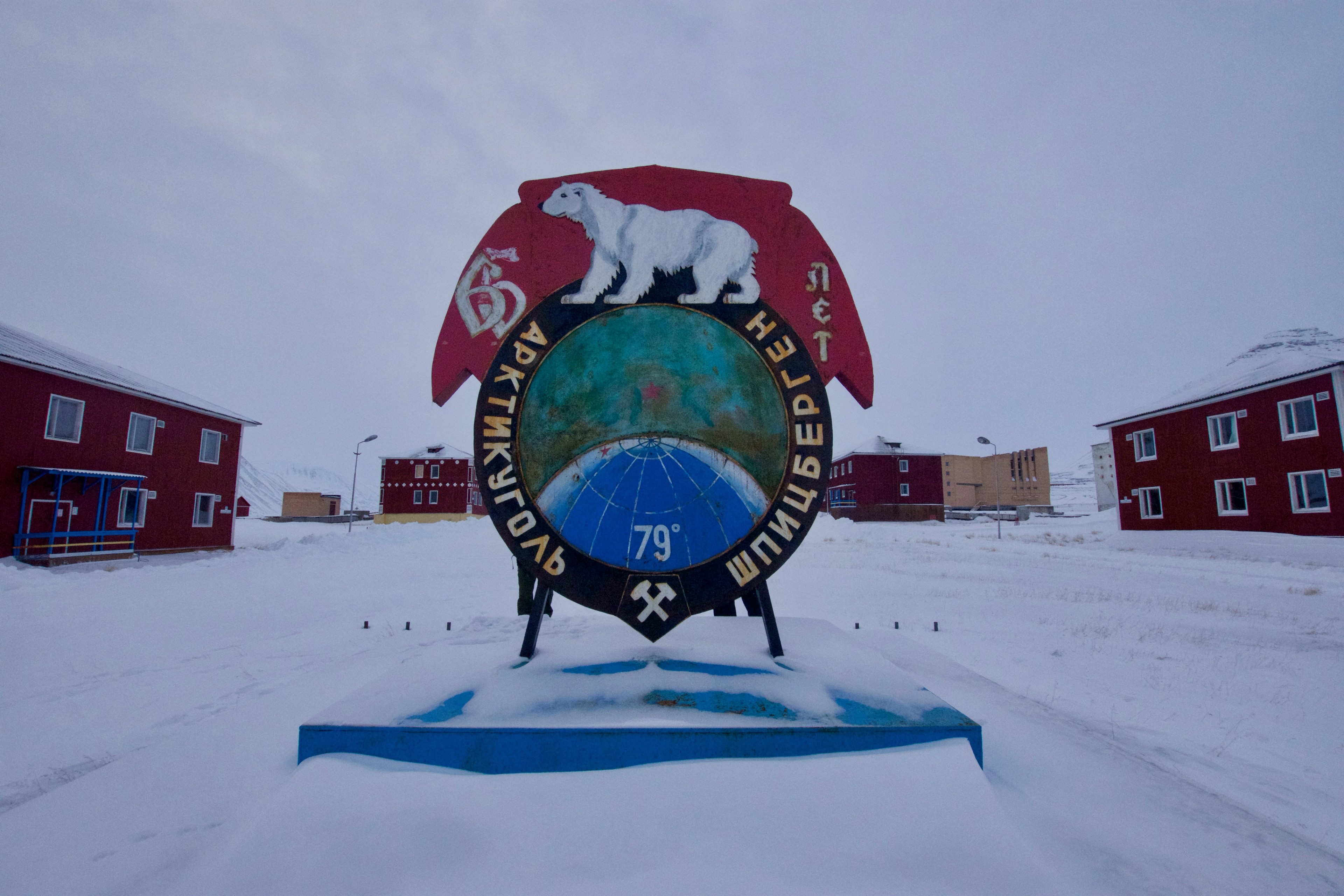 A circular illustrated sign stands among red buildings.
