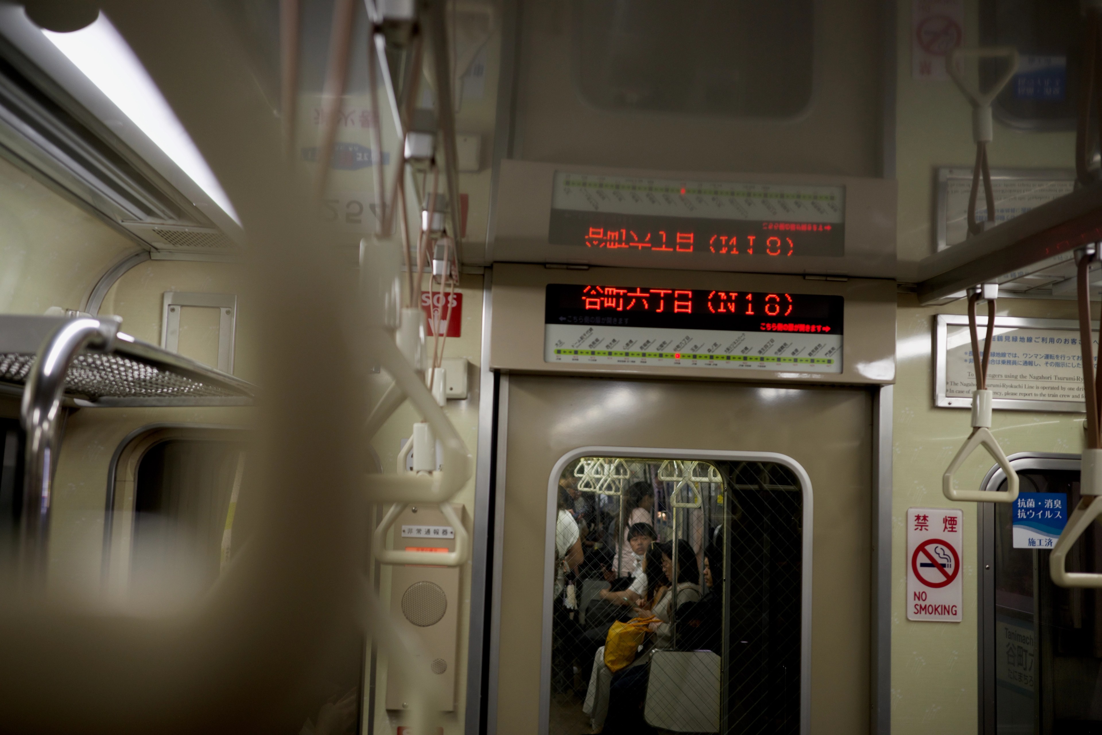 Passengers and hand straps inside a commuter train.