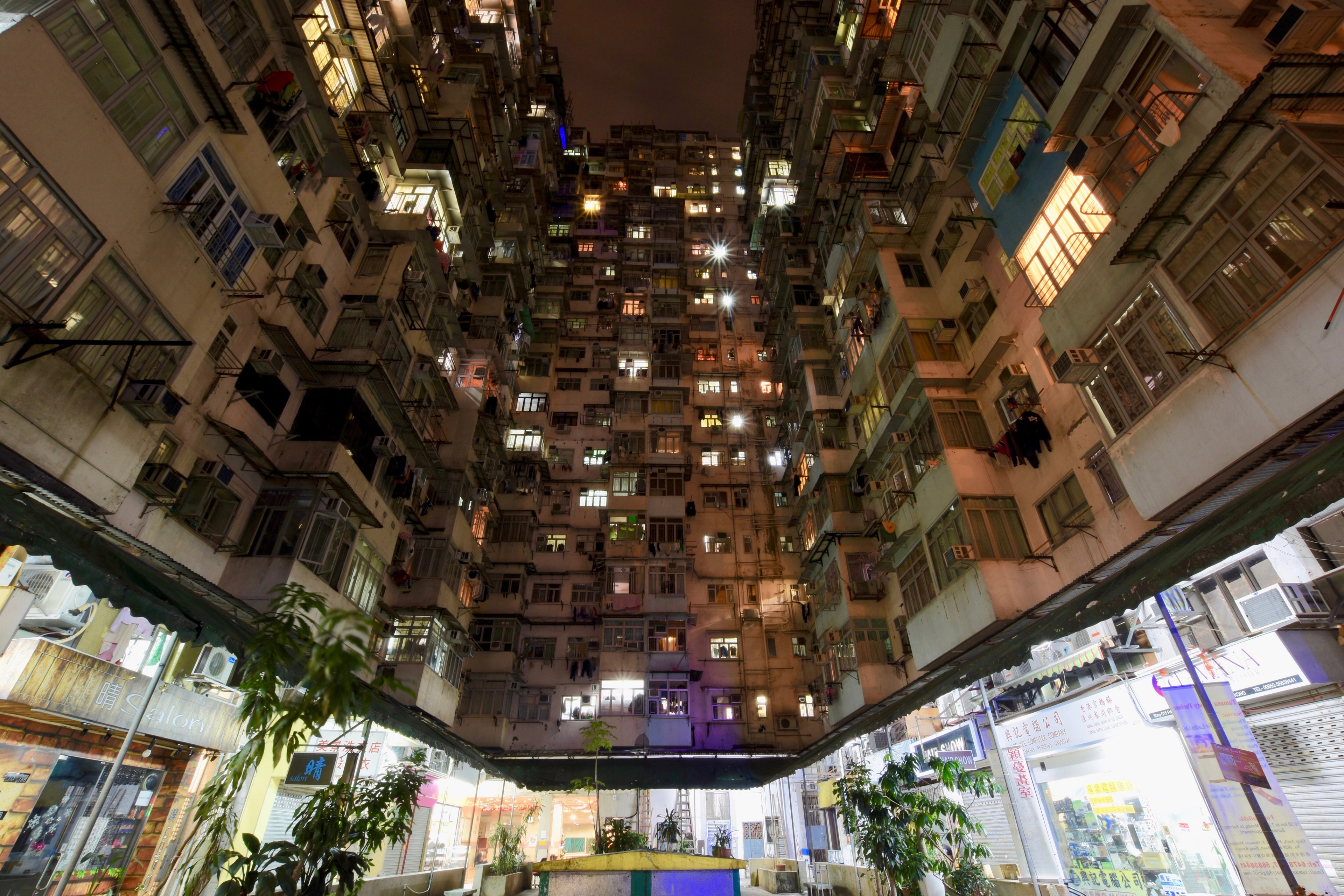 An upward view of dense residential towers enclosing a small open courtyard.