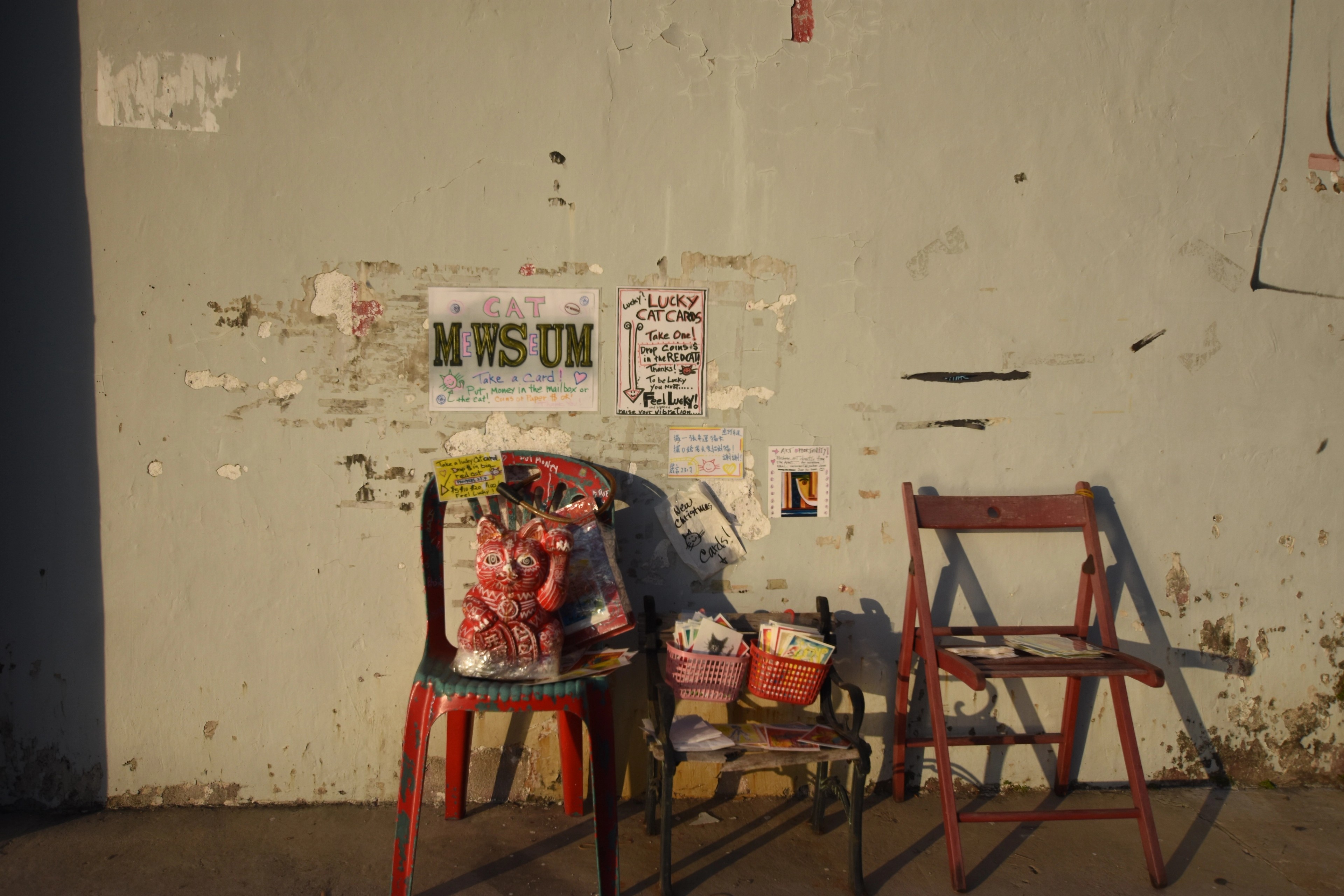 Folding chairs and small items sit outside a wall covered with notices.