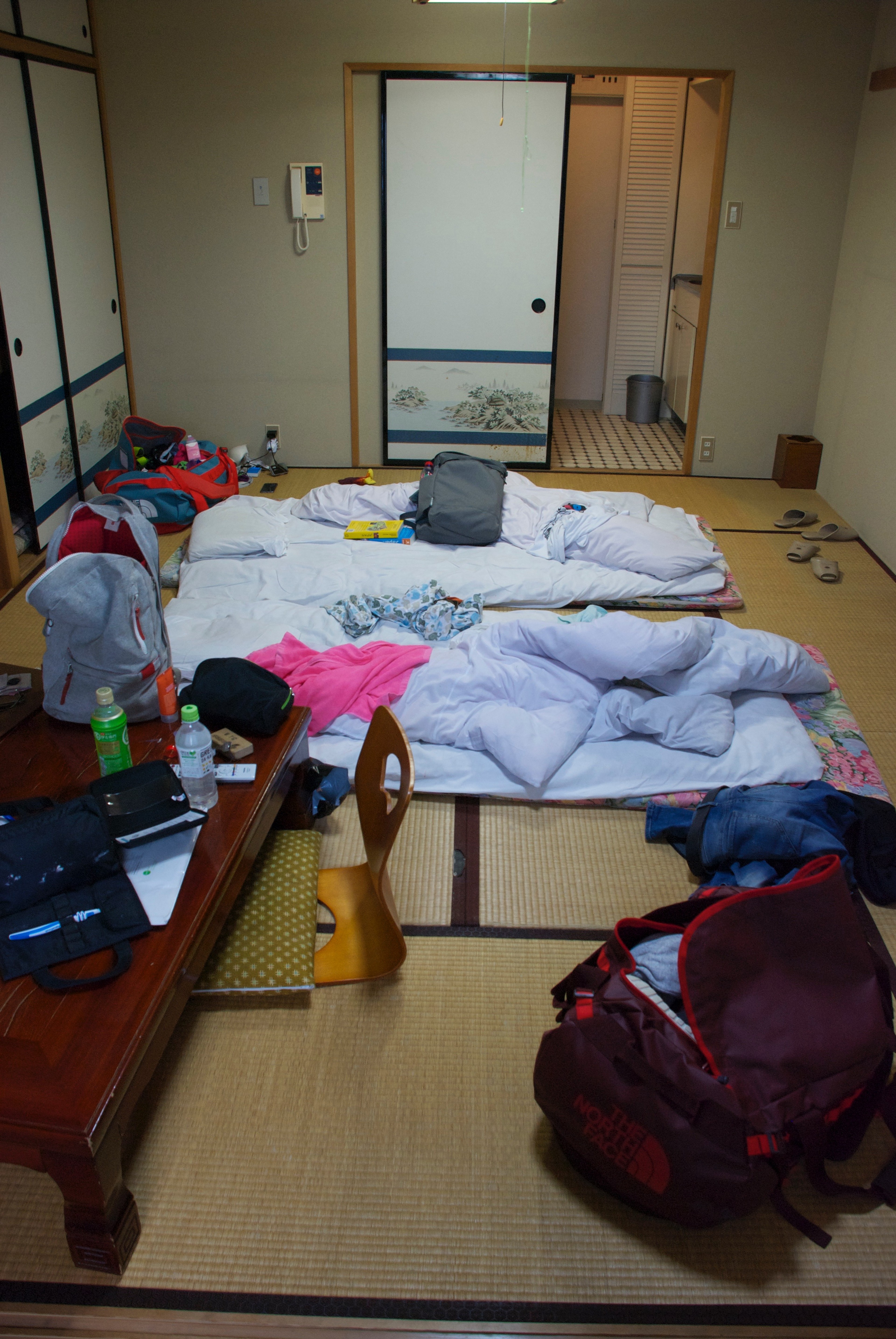 A small Japanese-style room is scattered with bags and bedding.