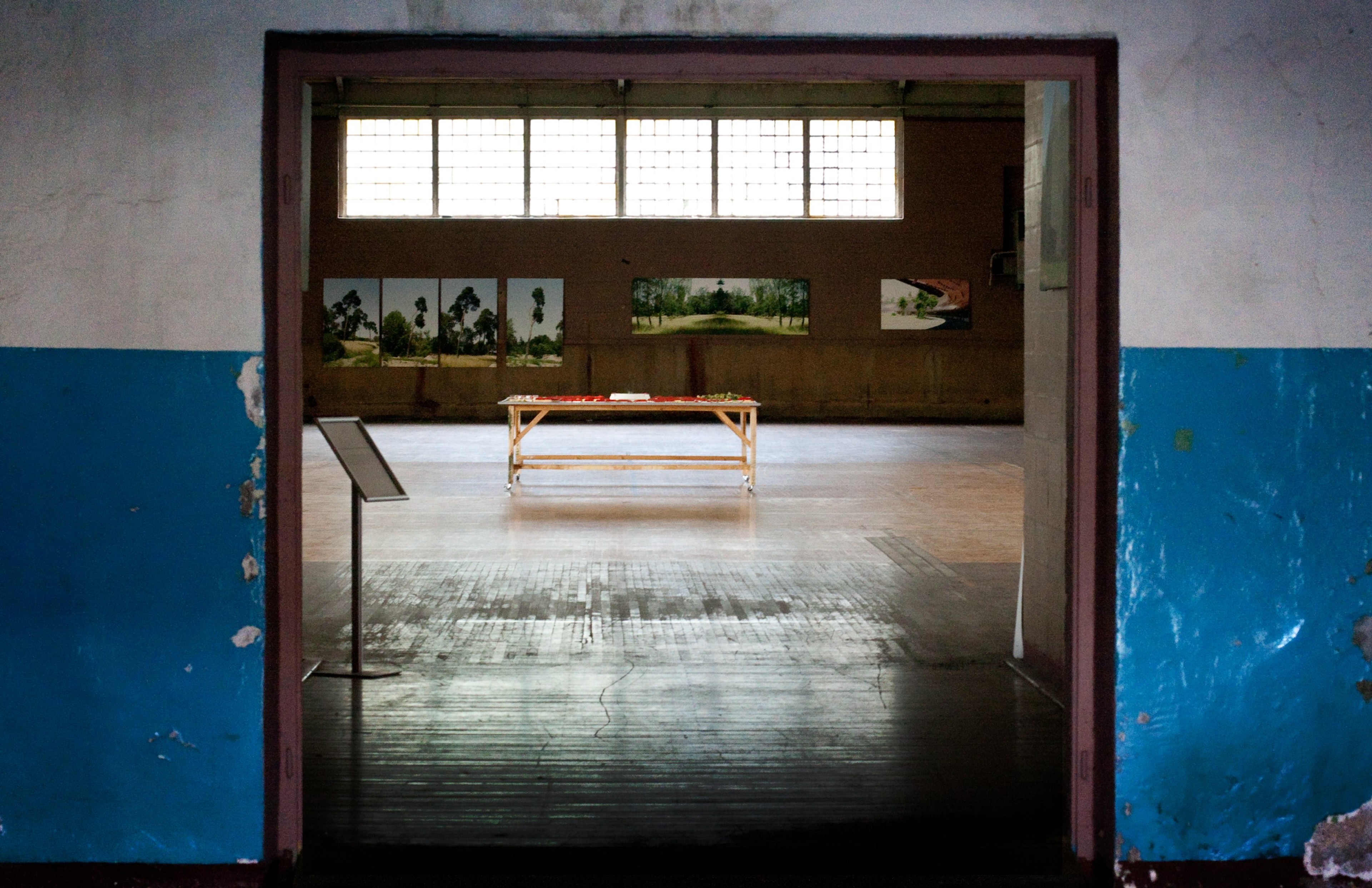 An open doorway reveals a simple room with a wooden floor and blue lower walls.
