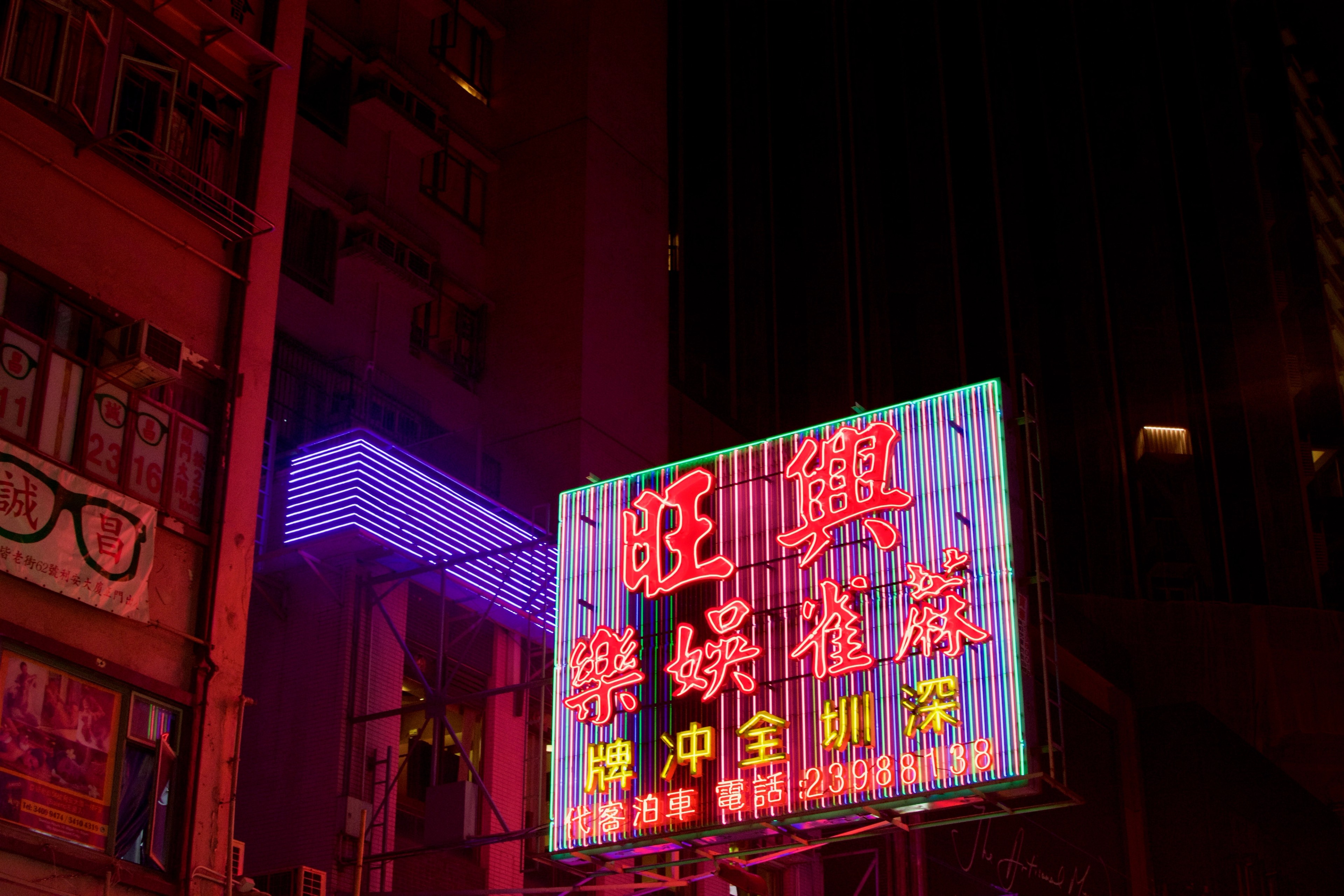 A large rectangular Chinese-language sign glows purple and red above the street.