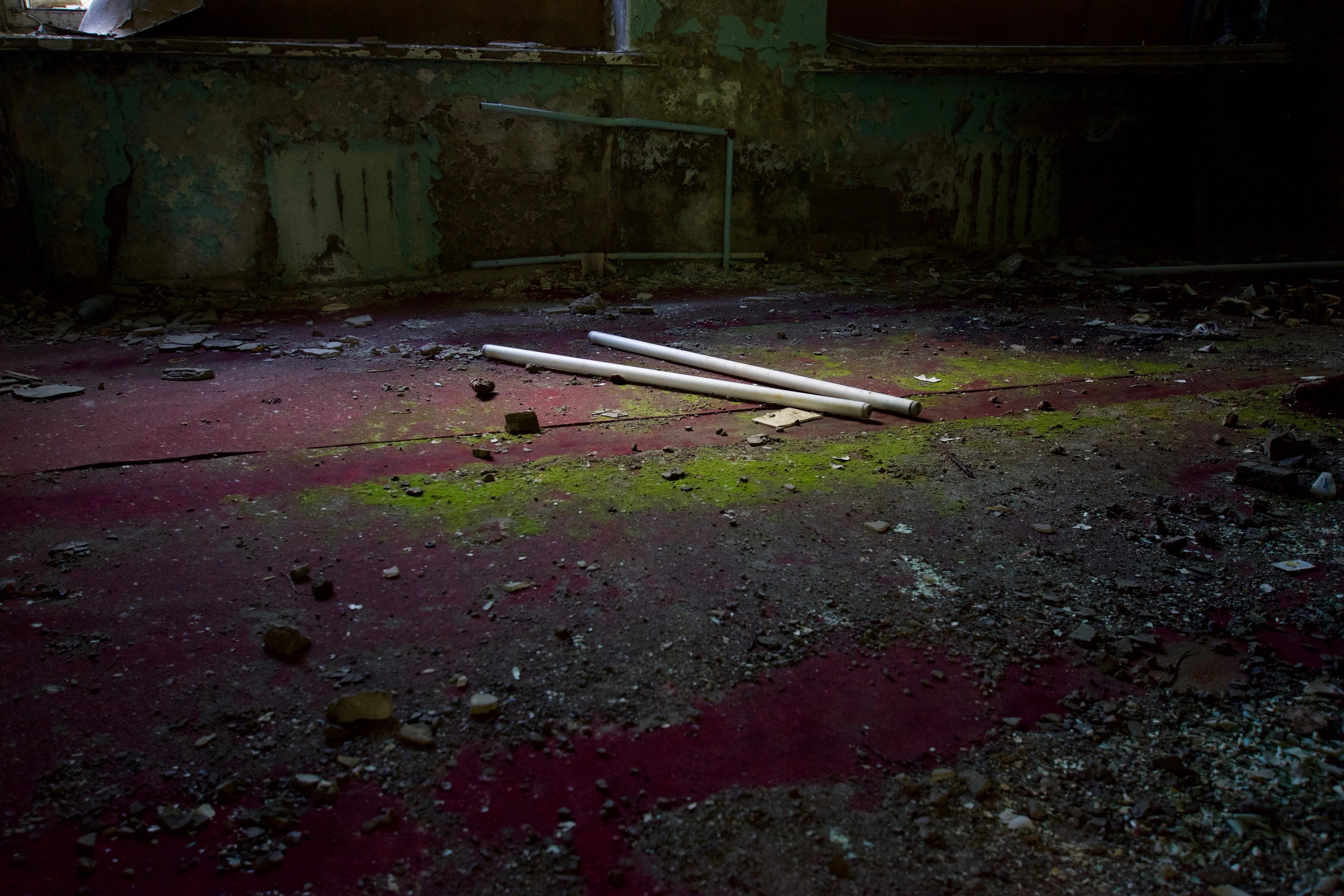 A dark room with a red-stained floor and fallen panel.