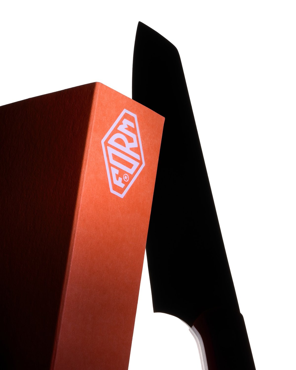 A black knife with a white "FORM" logo rests beside an orange box with a similar logo.
