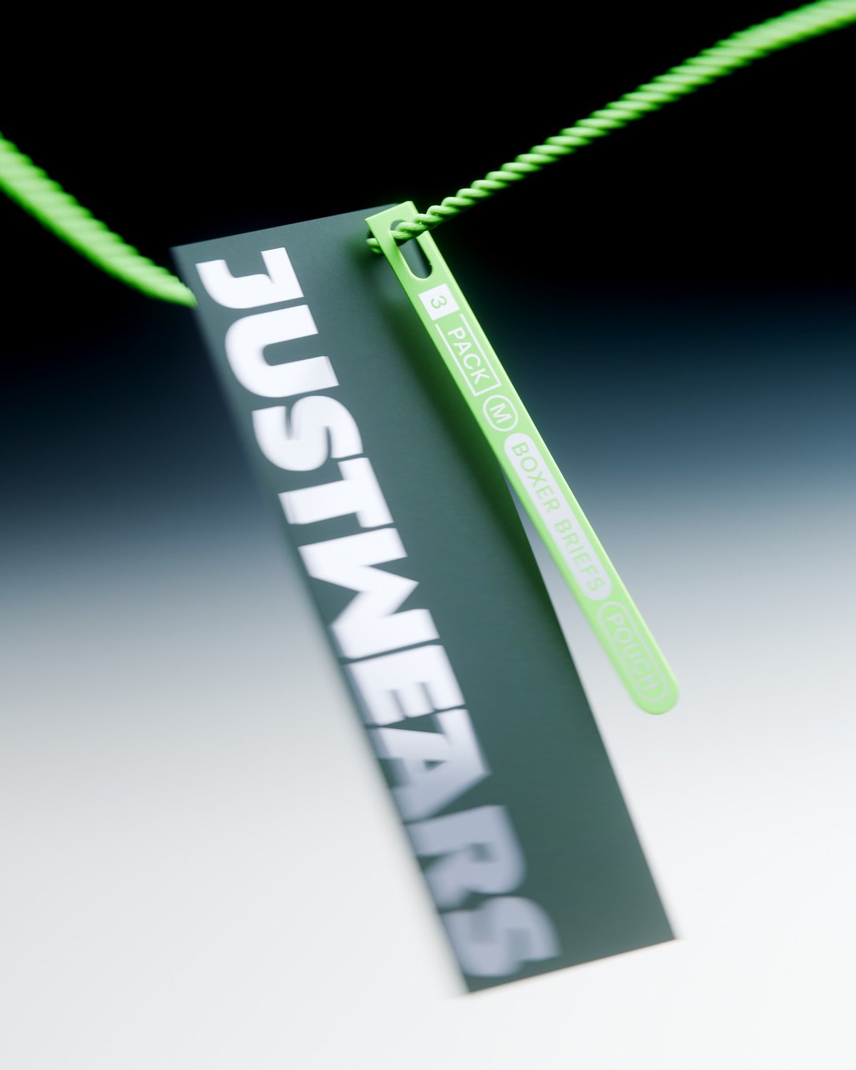 A green "JUSTWEARS" tag hangs from a green cord. The tag indicates "3 PACK M BOXER BRIEFS POUCH."
