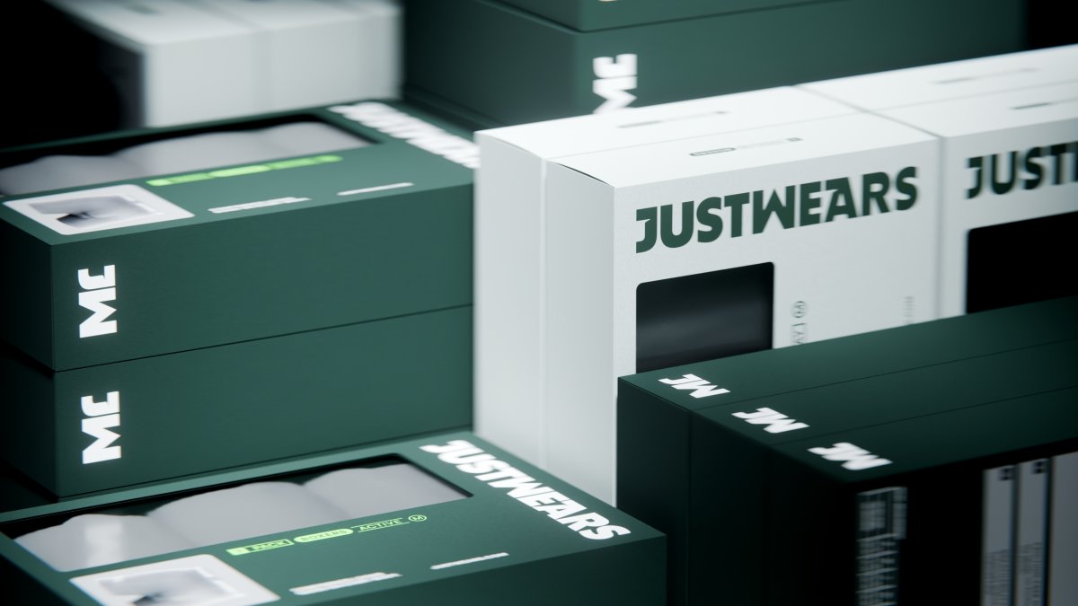 Multiple boxes of Justwears brand apparel are displayed, featuring white and dark green packaging with the brand name prominently displayed.