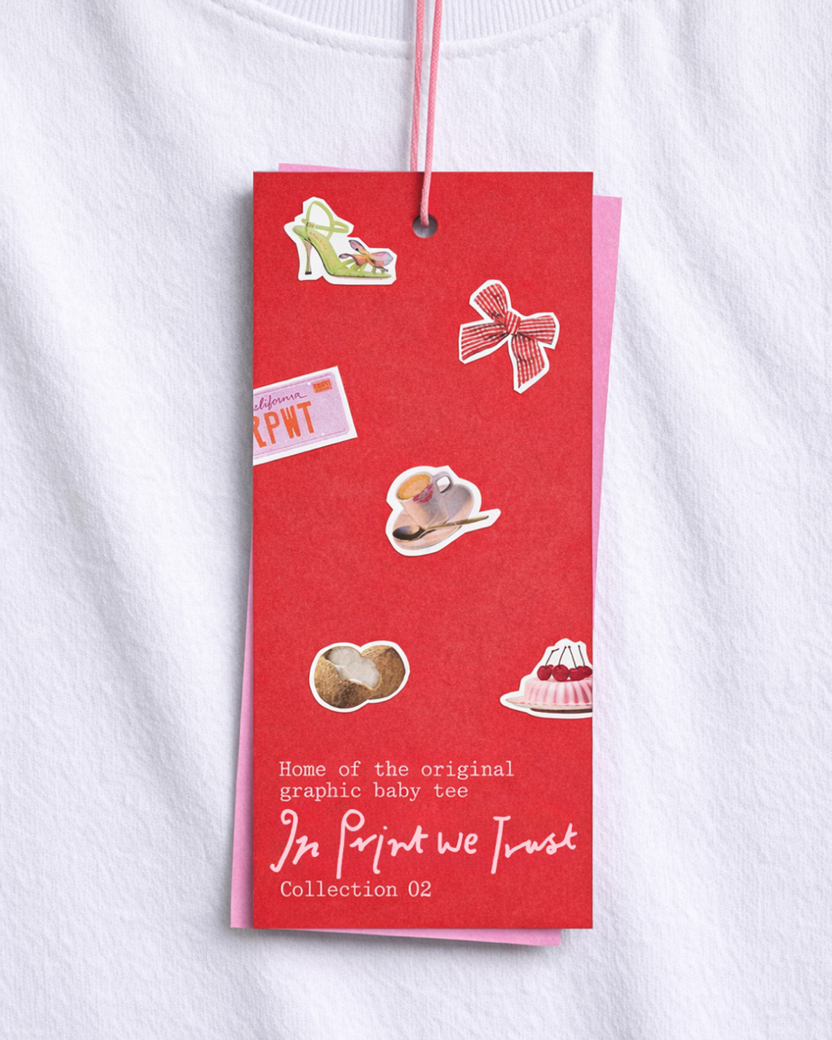 A red tag attached to a white t-shirt displays various graphics, including a high heel shoe, bow, cup, pastry, coconut, and cherries. The tag identifies the item as a "graphic baby tee" and indicat...