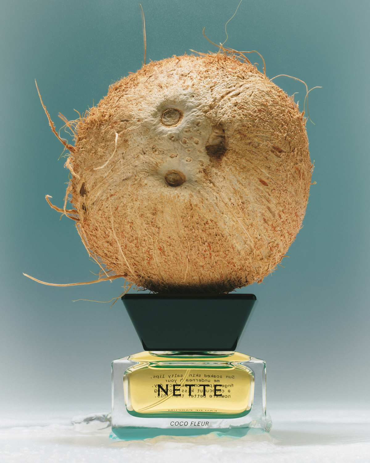 NETTE Coco Fleur perfume with coconut on teal background