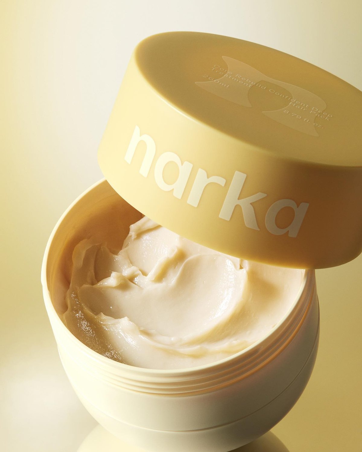 An open container of Narka Core Rebuild Confident Deep Treatment Hair Pack (8.79 fl.oz.) is shown, revealing a light beige, creamy substance.