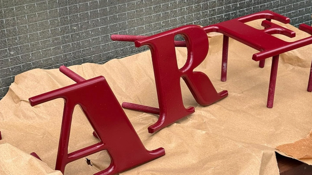 Chefs work in a commercial kitchen, preparing food at a stainless steel counter. Various ingredients, containers, and utensils are visible.