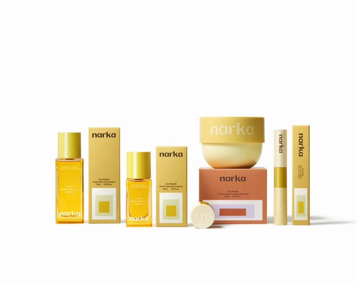 Narka's skincare products are displayed against a white background.  The collection includes bottles, boxes, a jar, a cream, and a tube, all in gold and beige packaging.