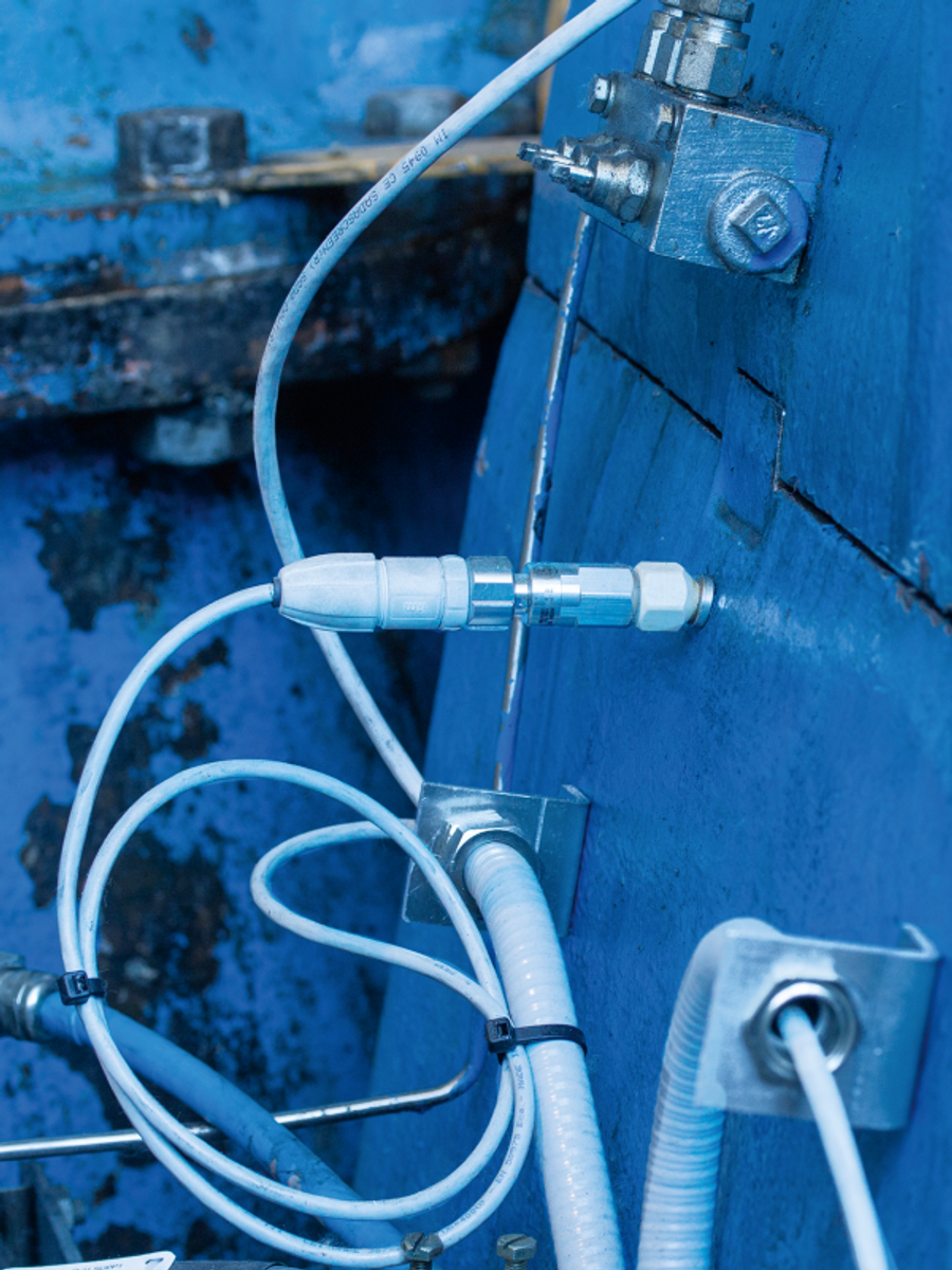 Schwingungssensor mit Kabel und Halterung an einem blauen Maschinengehäuse