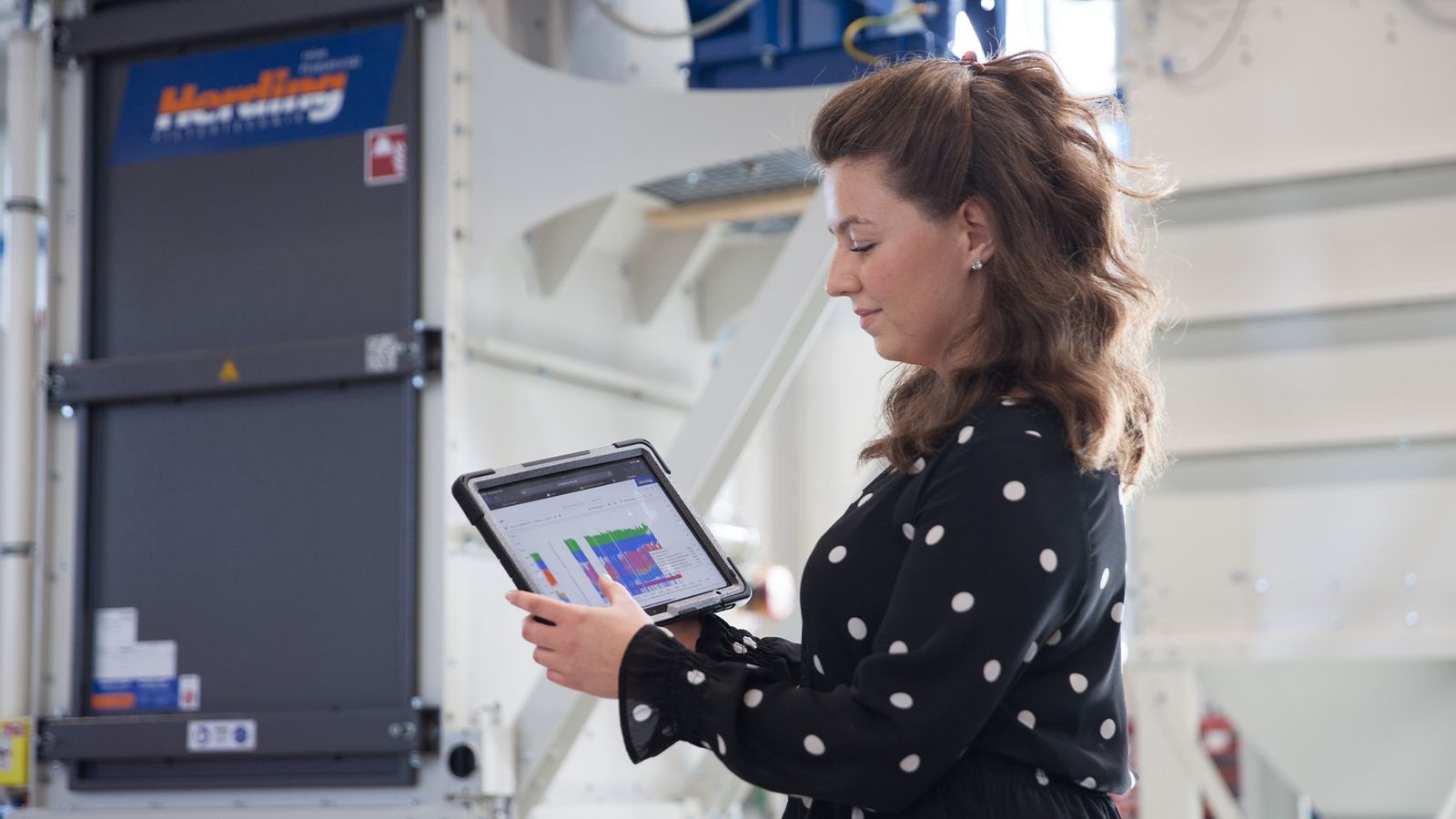 Female technician checking filter monitoring dashboard on tablet in front of Handling filter system