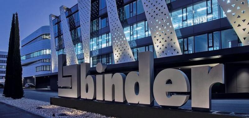 binder Unternehmensgebäude mit beleuchtetem Schriftzug bei Nacht