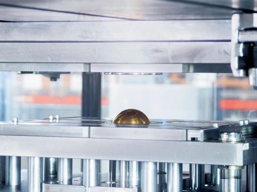 Nahaufnahme eines Presswerkzeugs mit geprägtem Metallteil zwischen den Pressplatten