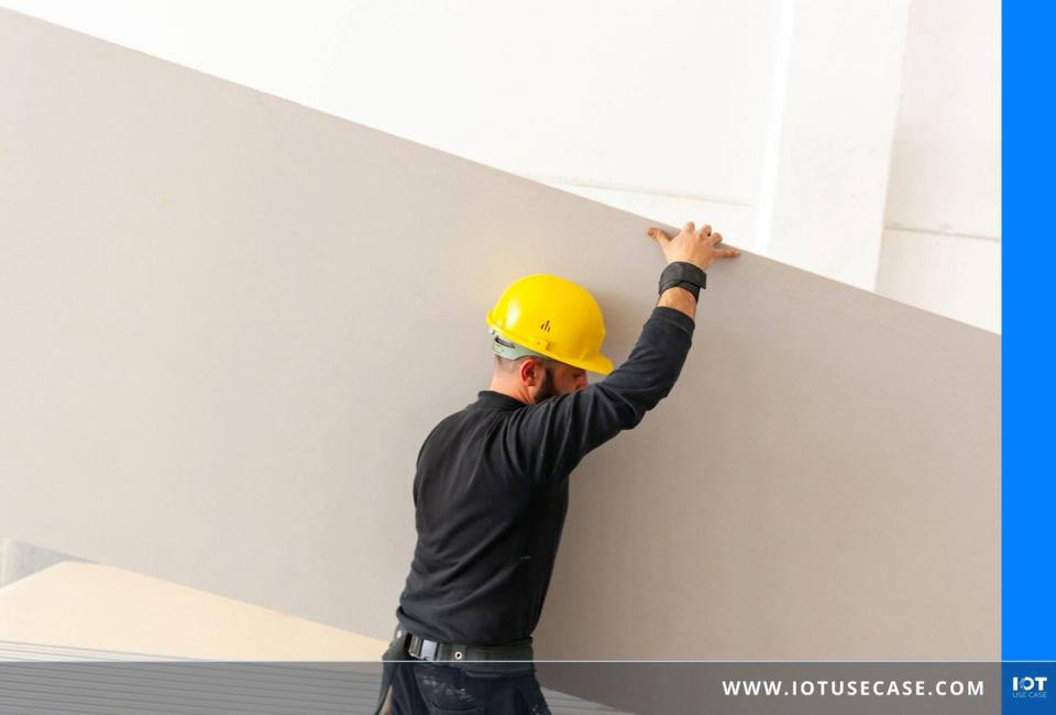 Worker in yellow hard hat installing drywall panels on a construction site