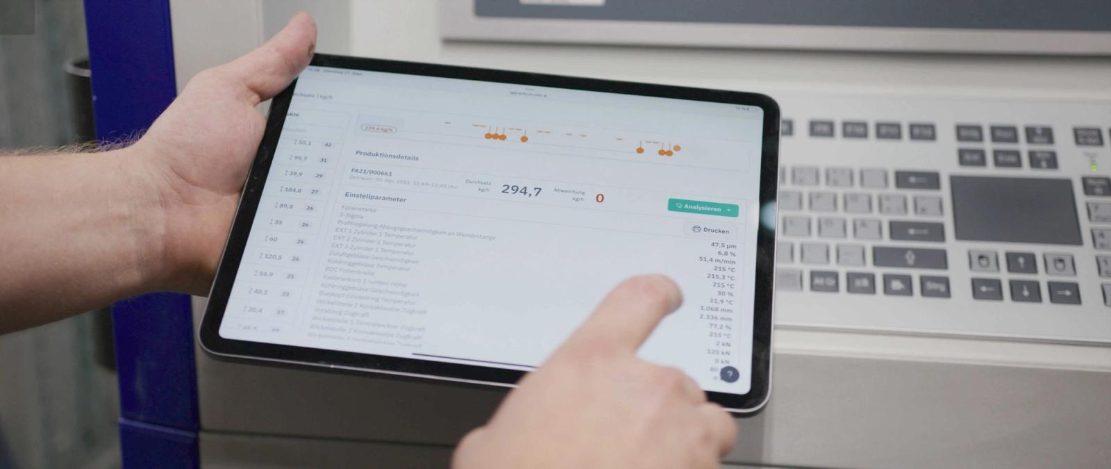 ENLYZE Werker-Tablet mit Einstellparameter-Übersicht neben Maschinenbedienfeld bei mk Plast