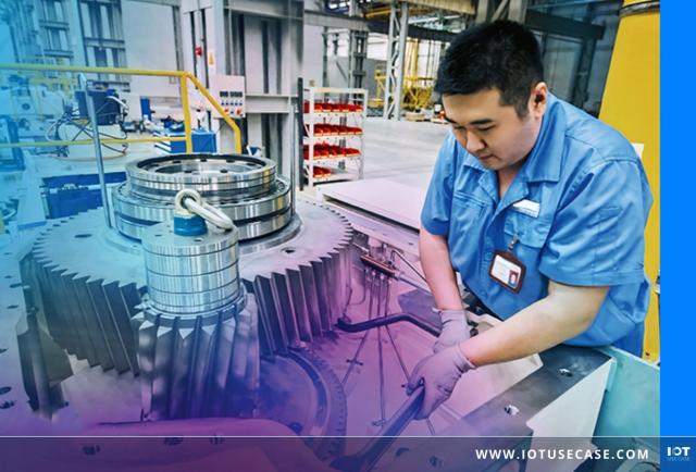 Techniker in blauer Arbeitskleidung montiert in einer Industriehalle ein großes Zahnrad-Getriebe.