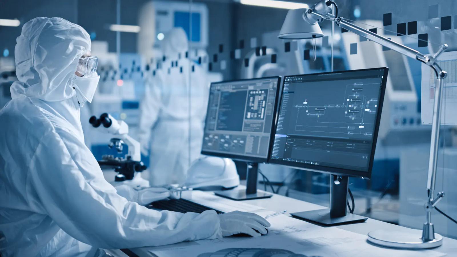 Pharmaforscher in Reinraum an Dual-Monitor-Workstation mit Track-and-Trace-Software