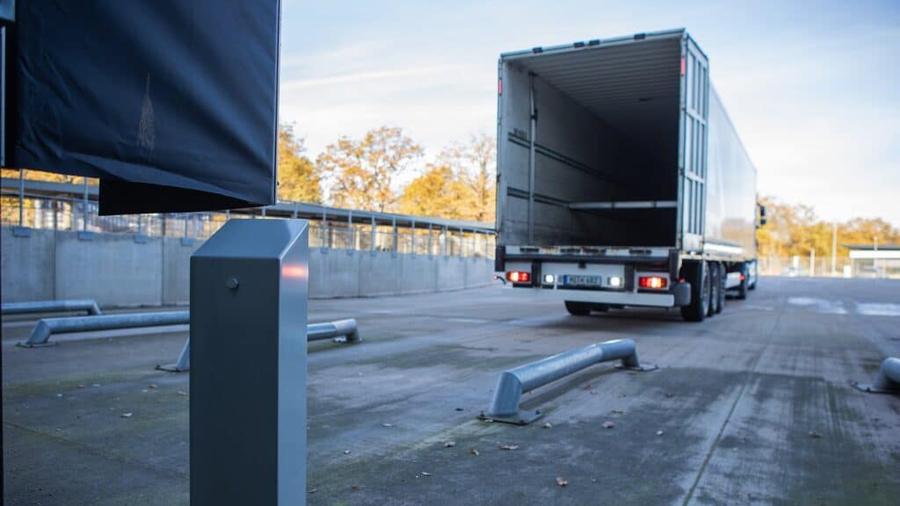 Lkw mit geöffnetem Auflieger am Verladehof mit Kamera-Sensorpfosten im Vordergrund
