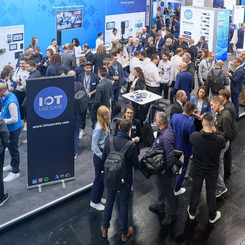 Many visitors talking at a previous IoT Use Case IoT Meet-Up, with an IoT Use Case roll-up banner in the foreground