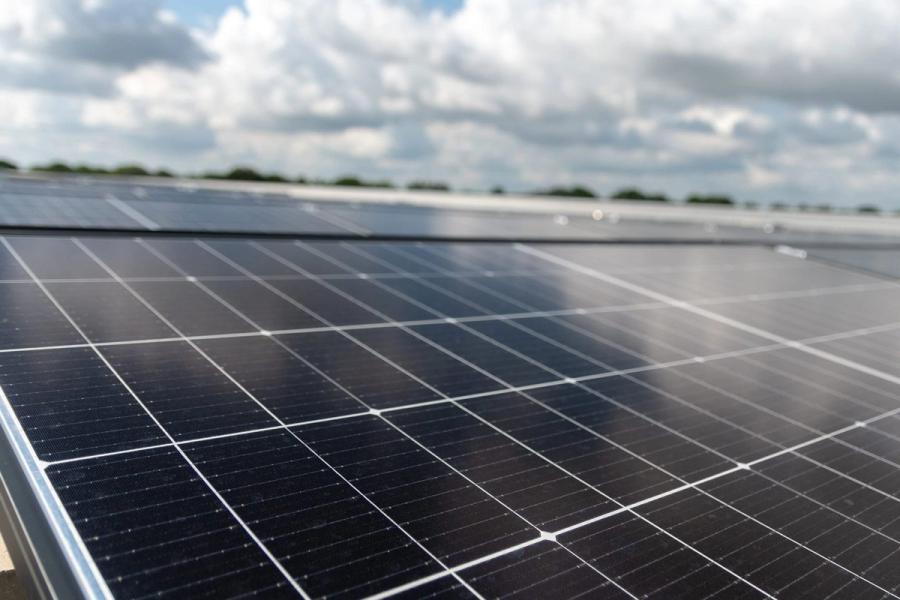 Nahaufnahme von Solarmodulen auf einem Flachdach vor bewölktem Himmel