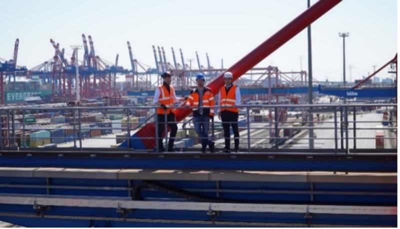 Three igus engineers on container crane at Port of Hamburg with safety equipment