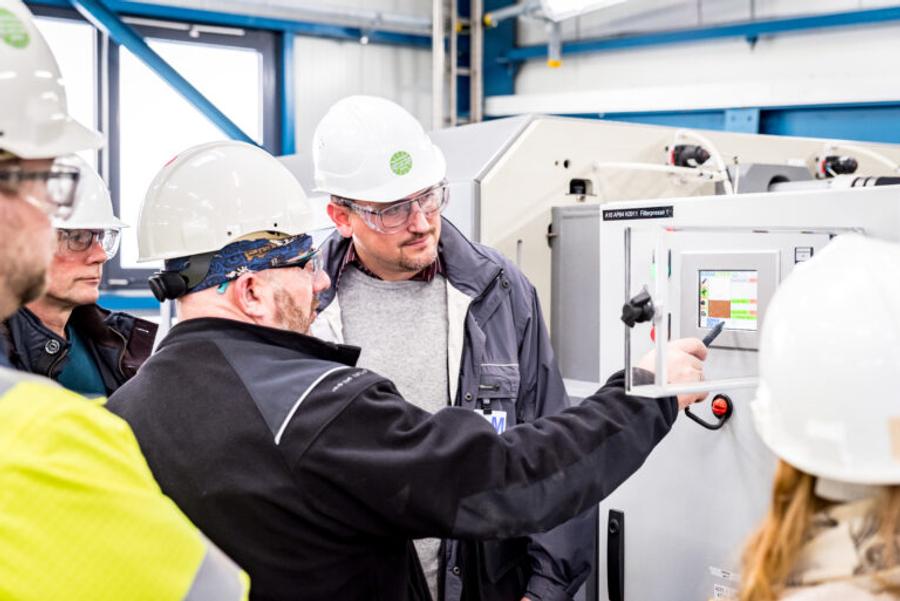 Gruppe von Mitarbeitenden mit Schutzhelmen am Bedienpanel einer Filterpresse