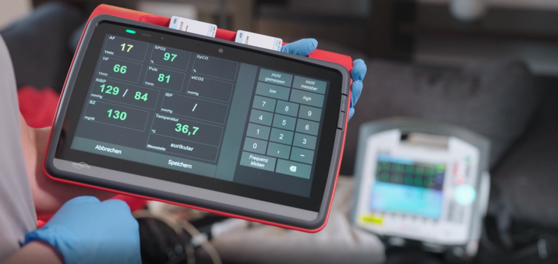 Sanitäter hält Notfallmedizin-Tablet mit Patientenvitalwerten im Rettungswagen