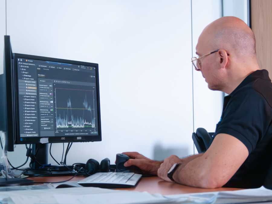 Mann am Schreibtisch betrachtet die Monitoring-Software am Bildschirm