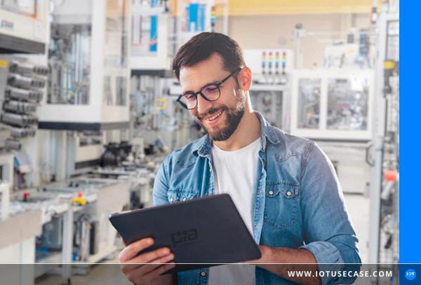 Service technician with a tablet in front of screens at a PIA Automation production line using the locally installed Maintenance App