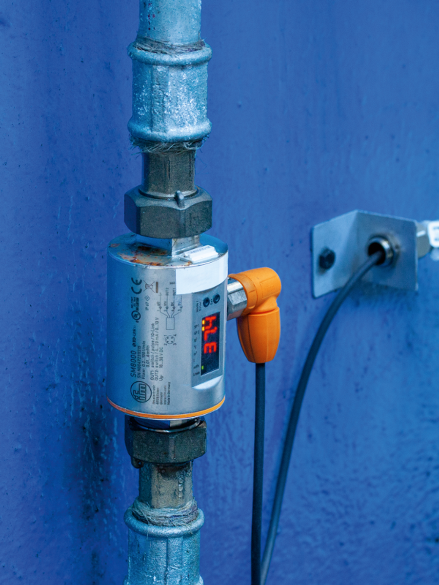 ifm-Sensor mit Display und orangem Anschluss an einer blauen Rohrleitung